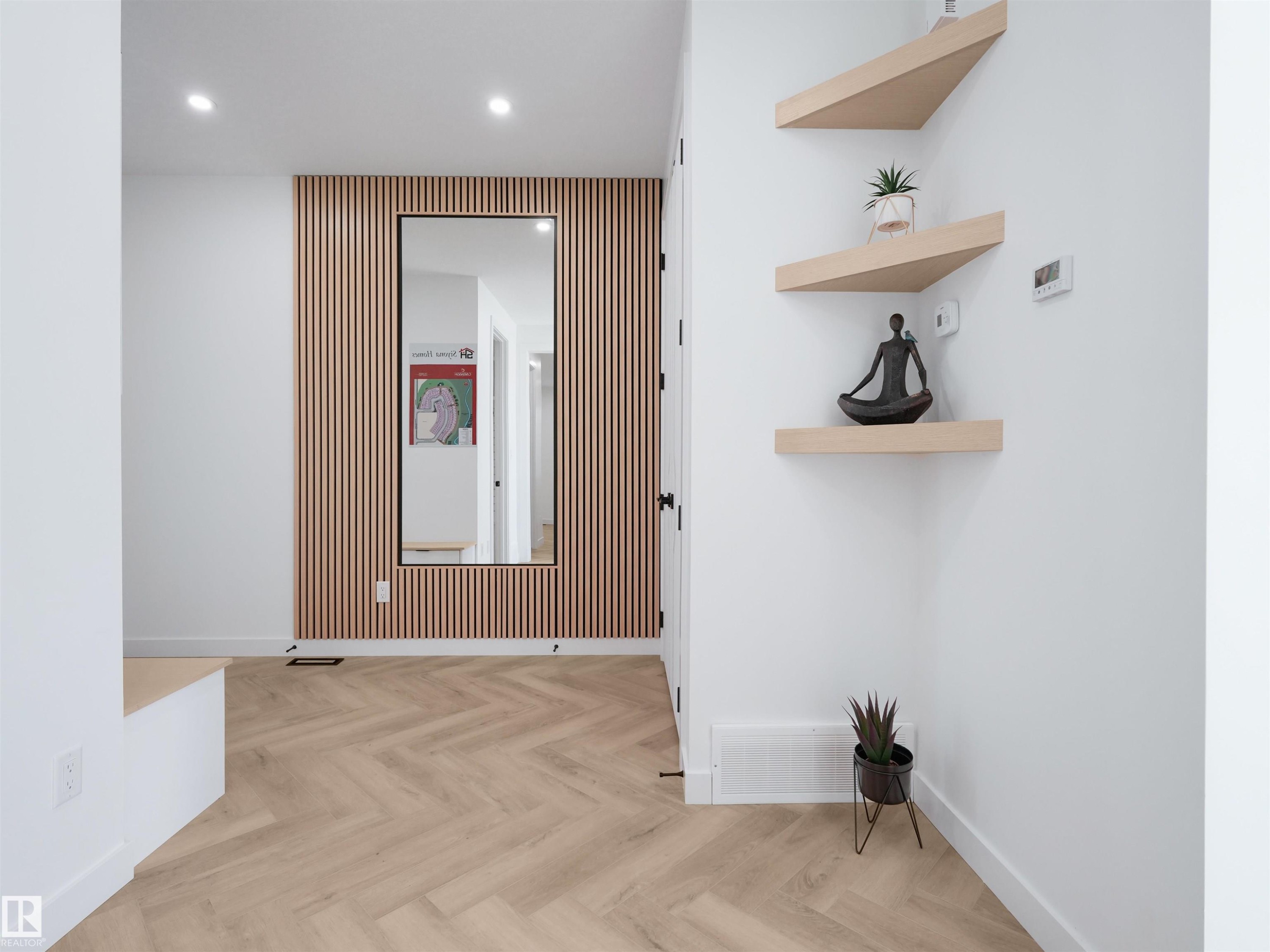 Herringbone wood-finish flooring complements the modern slat accent wall - 2070 Collip Crescent Sw, Edmonton, AB - Indoor Photo Showing Other Room