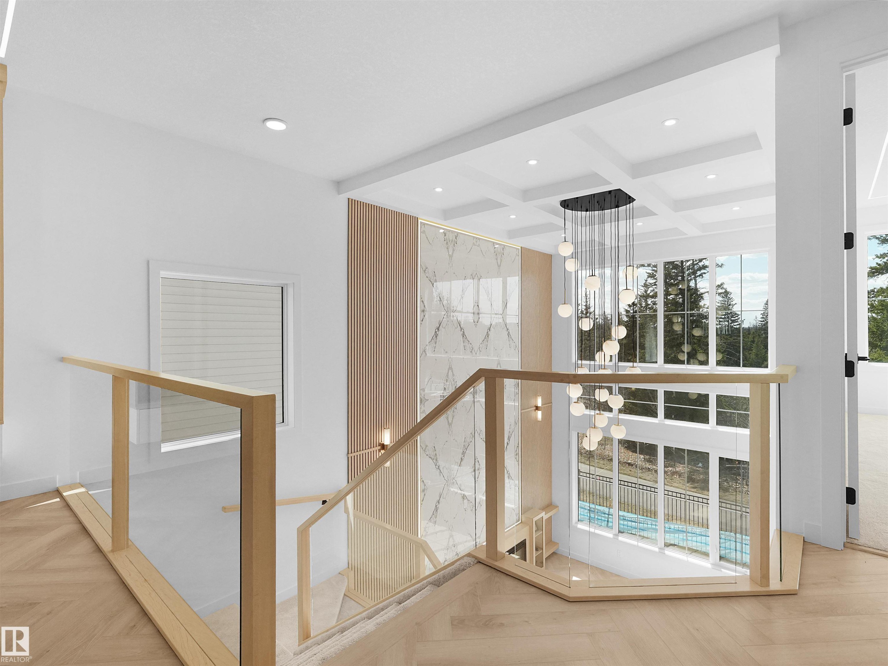 Two-story foyer featuring a striking chandelier, coffered ceiling, hardwood flooring, and glass panel railings with light wood newel posts - 2070 Collip Crescent Sw, Edmonton, AB - Indoor Photo Showing Other Room