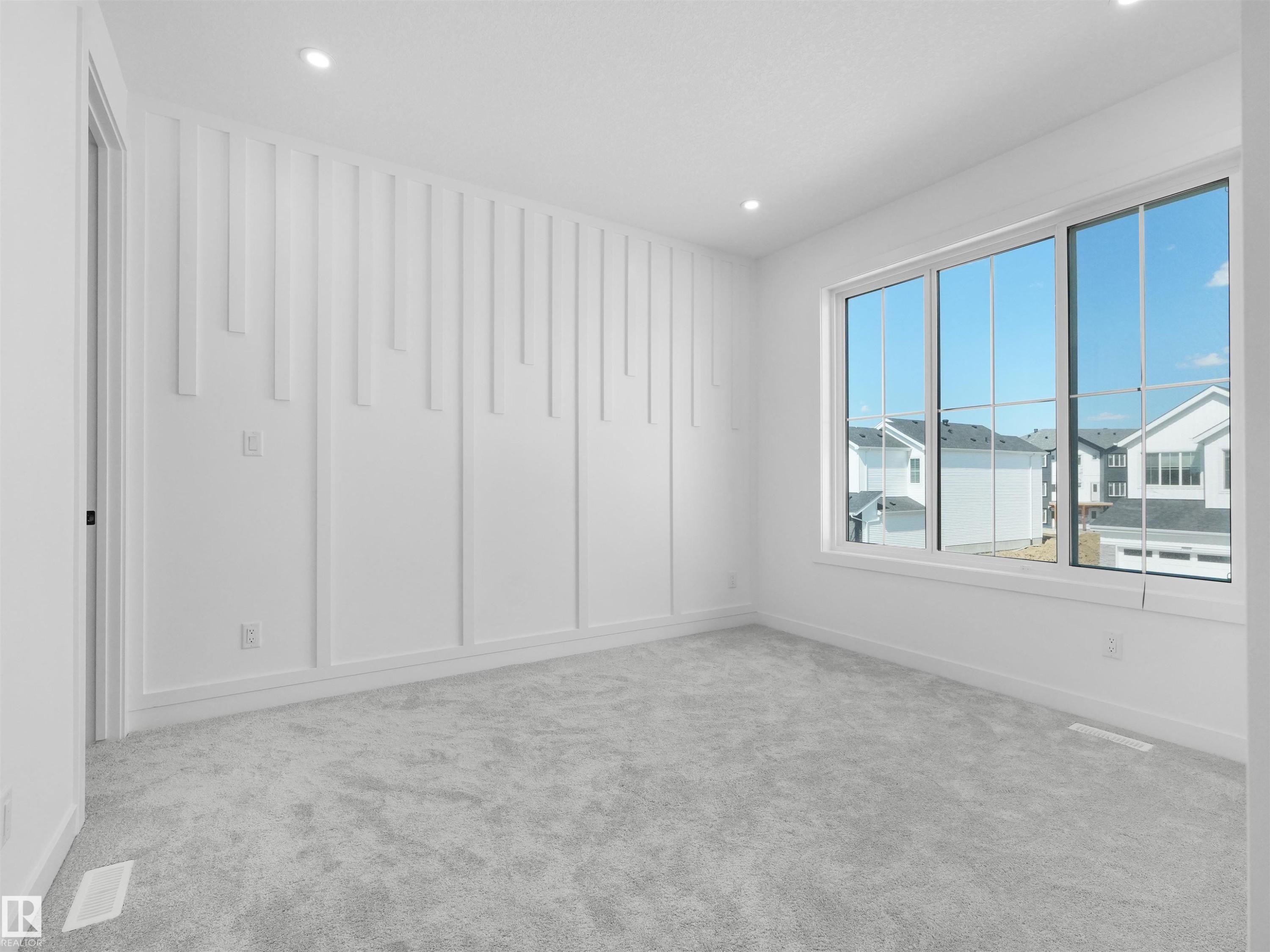 Bright interior space featuring a large multi-pane window, recessed lighting, and a textured accent wall - 2070 Collip Crescent Sw, Edmonton, AB - Indoor Photo Showing Other Room