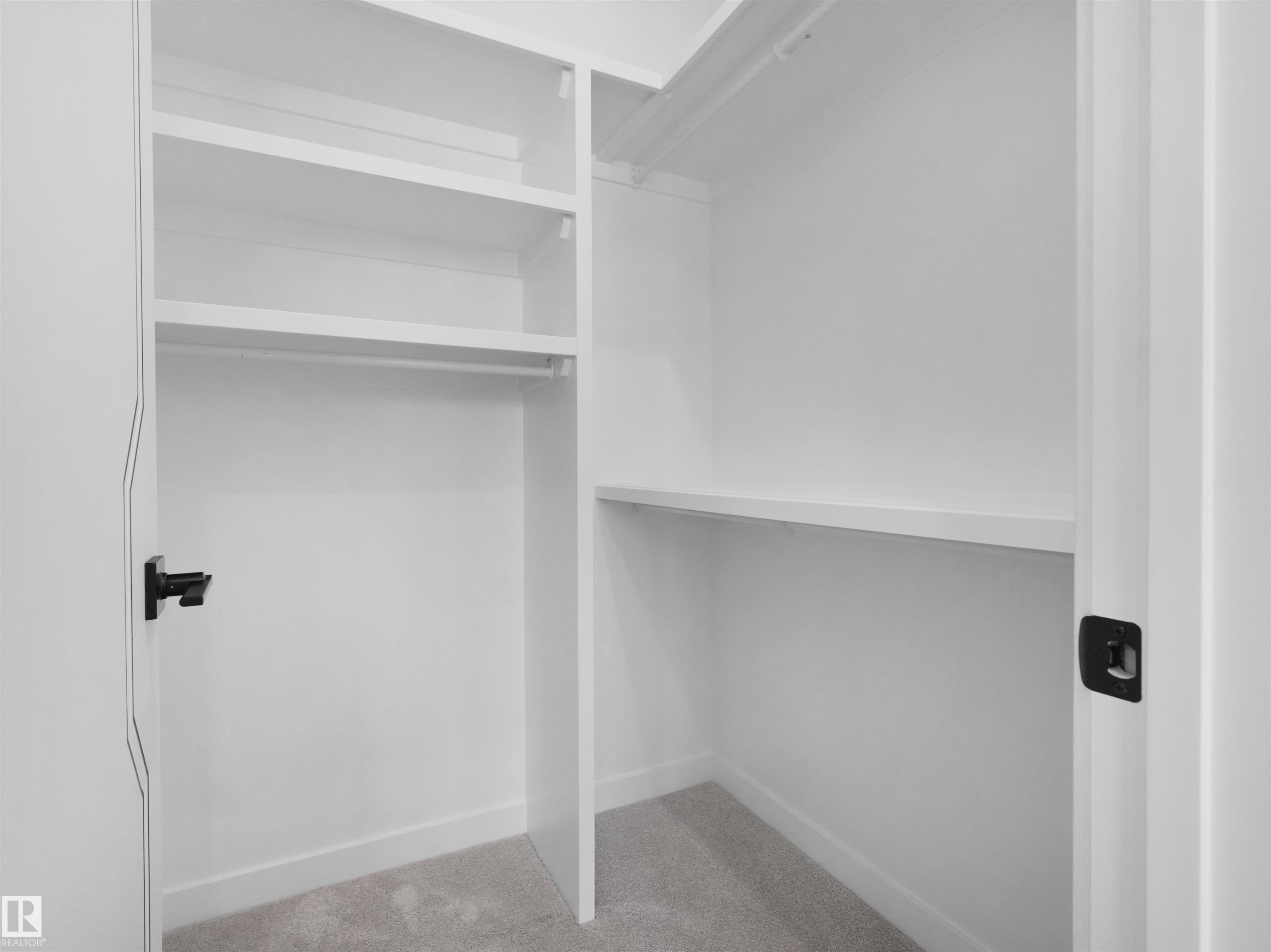 White built-in closet system featuring multiple shelving units, hanging rods, and a soft gray carpeted floor - 2070 Collip Crescent Sw, Edmonton, AB - Indoor With Storage