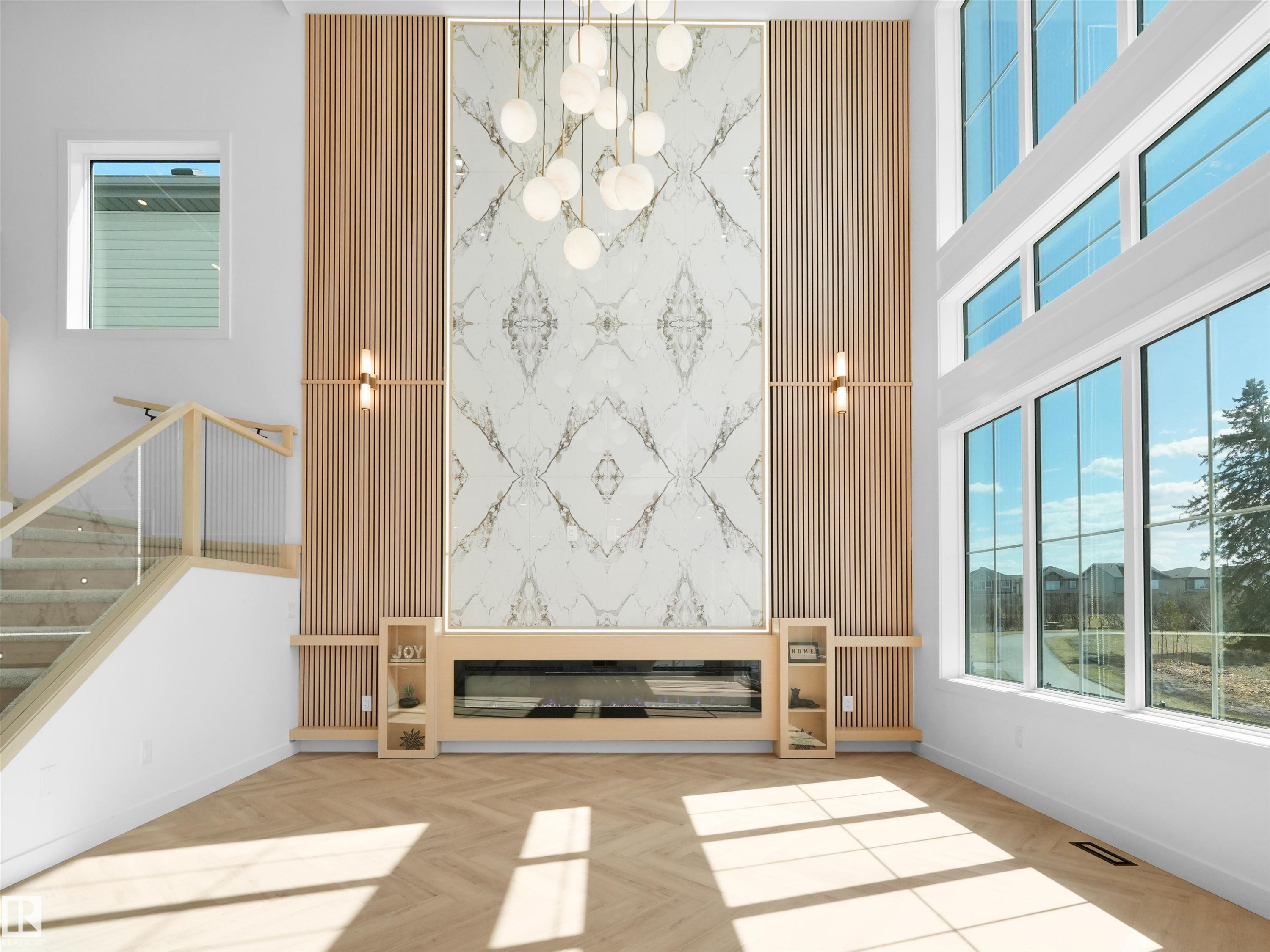 Two-story living area featuring a prominent fireplace wall with a built-in electric fireplace and decorative stone-like paneling - 2070 Collip Crescent Sw, Edmonton, AB - Indoor Photo Showing Other Room