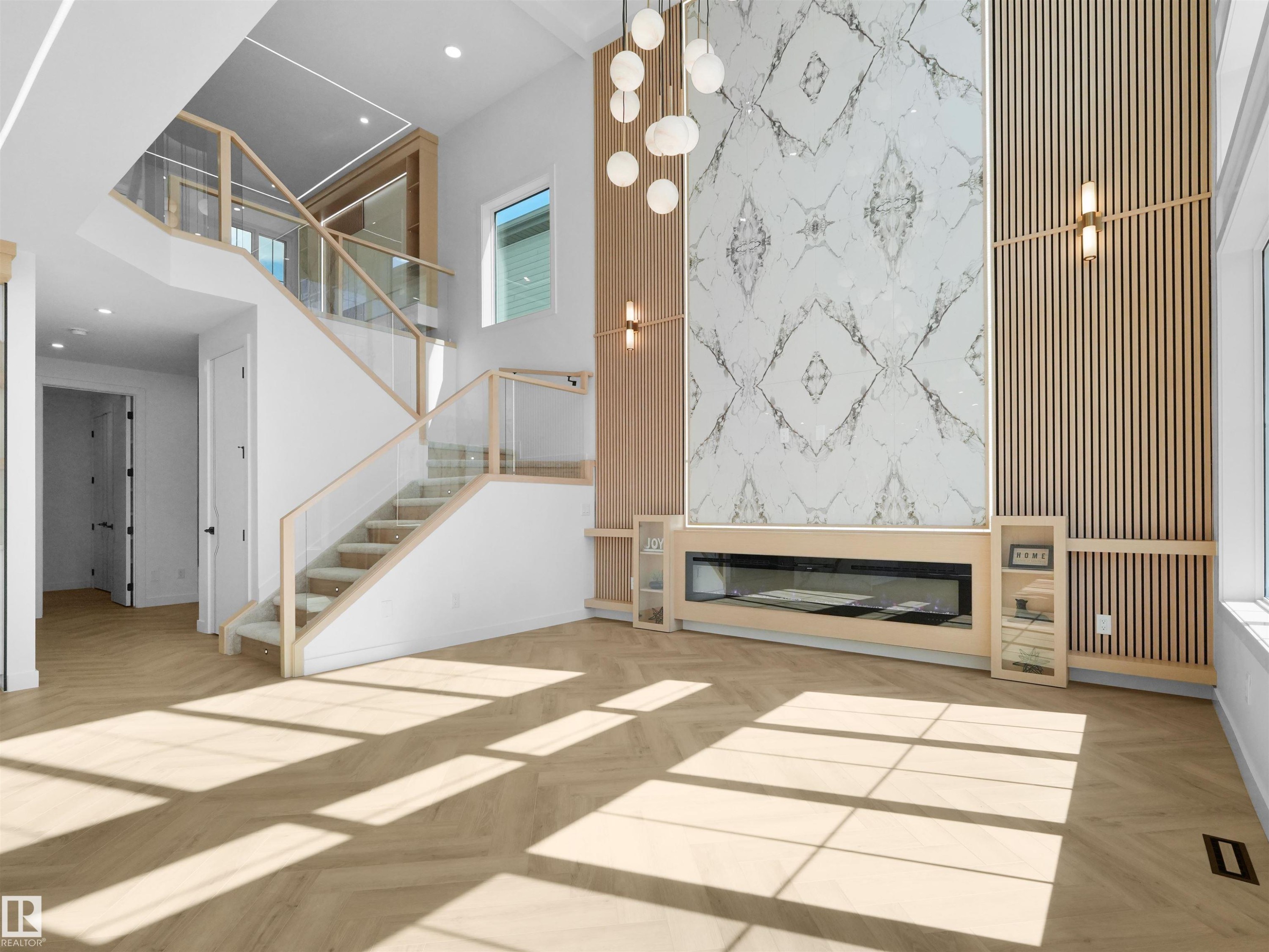 Two-story living area featuring a prominent fireplace wall with patterned stone and vertical wood slat accents - 2070 Collip Crescent Sw, Edmonton, AB - Indoor Photo Showing Other Room With Fireplace