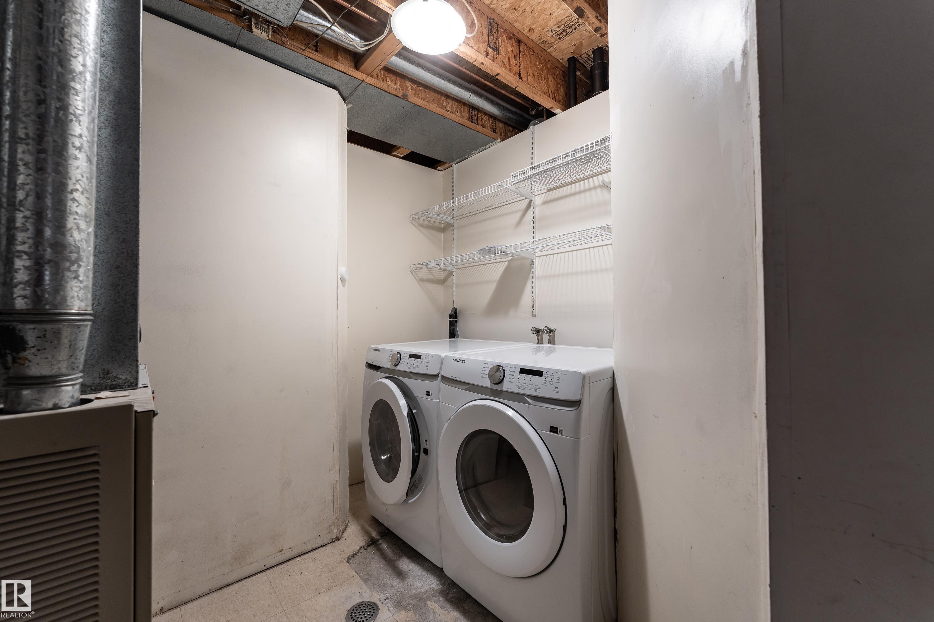 Dedicated laundry area featuring a washer and dryer, wire shelving, and a concrete floor - #63 1033 Youville Dr W Nw, Edmonton, AB - Indoor Photo Showing Laundry Room