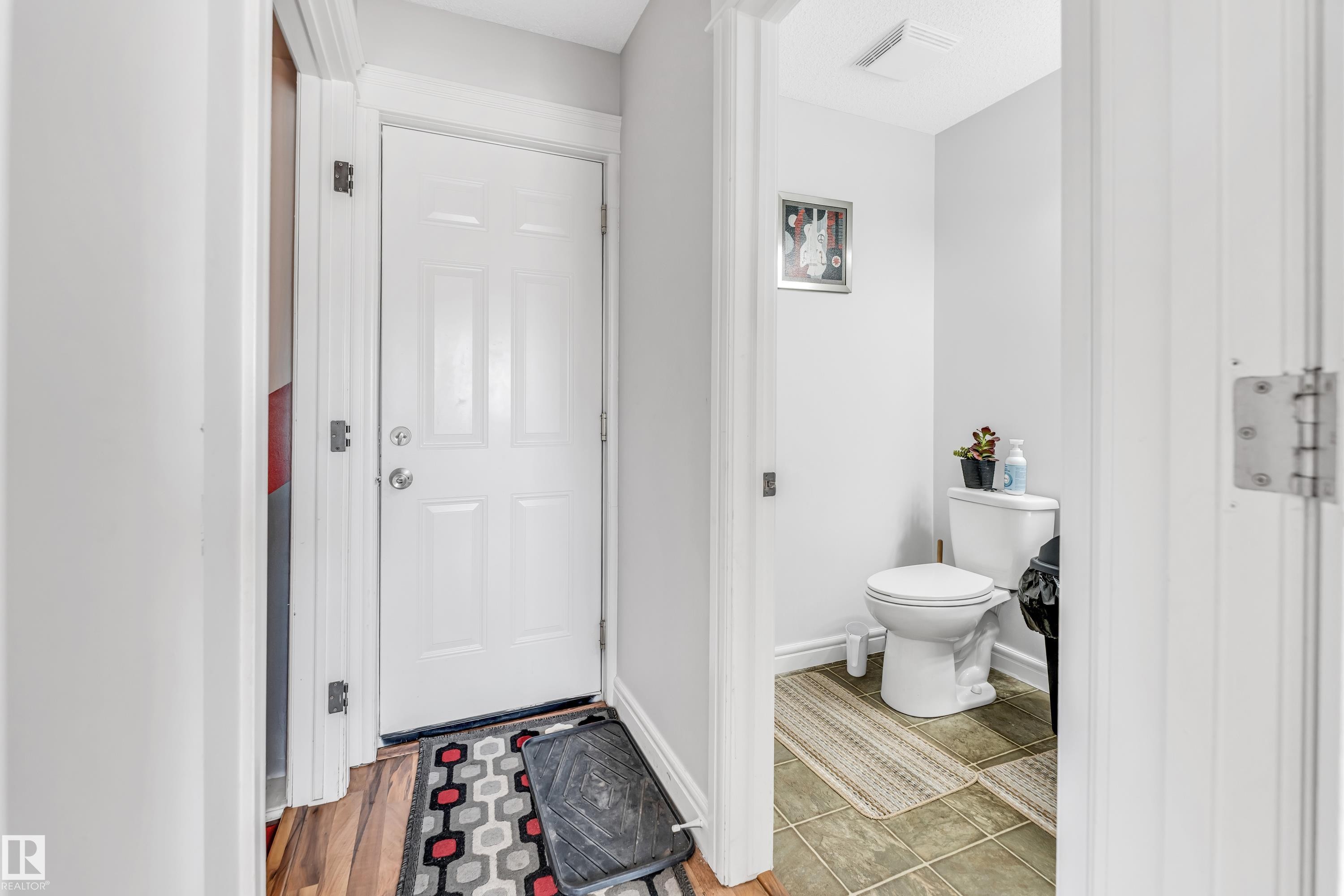 Entryway featuring a paneled door with polished hardware, wood-finish flooring, and light gray wall paint - 1921 119A Street, Edmonton, AB