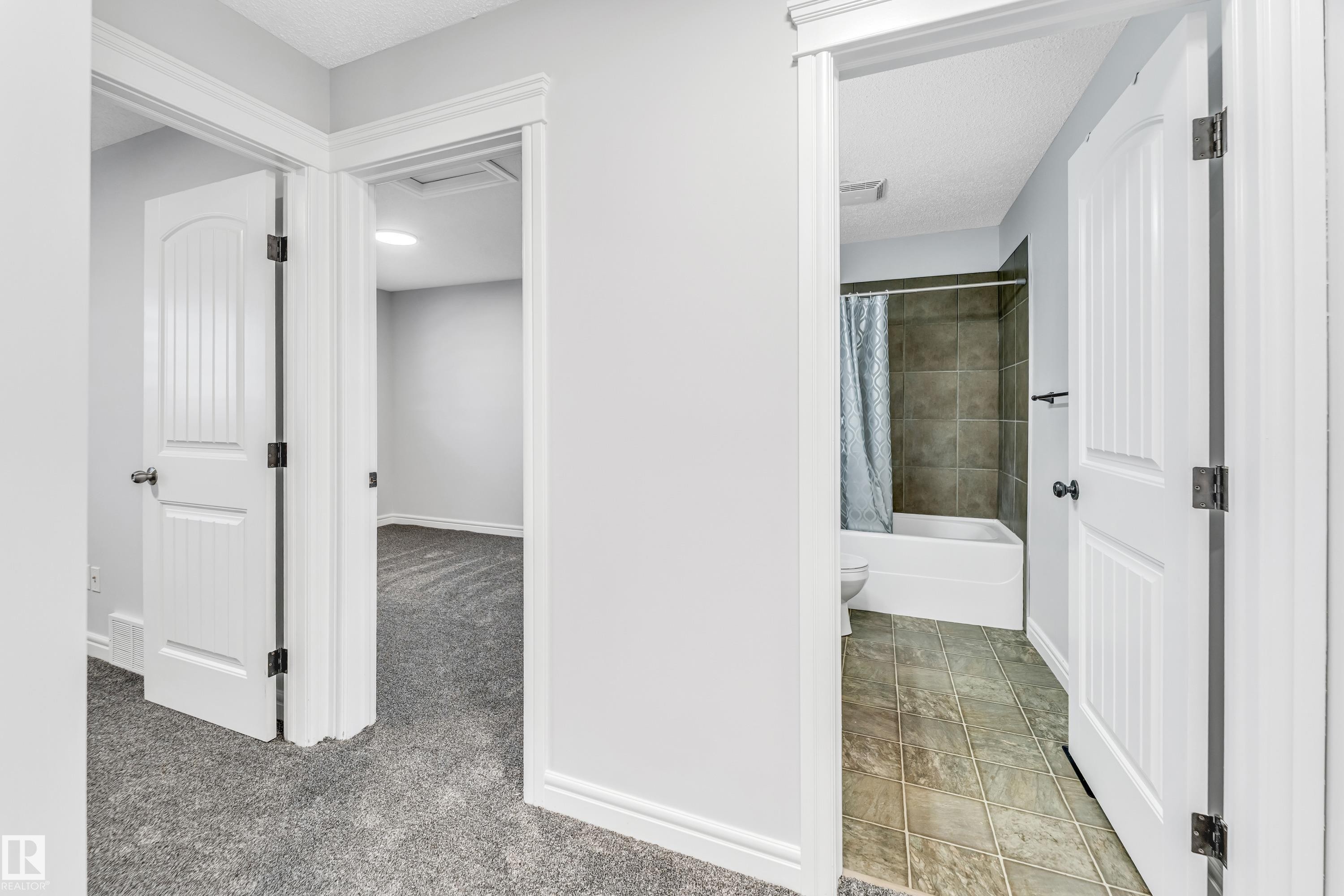 Bathroom with a full tub and shower, complemented by square floor tiling - 1921 119A Street, Edmonton, AB