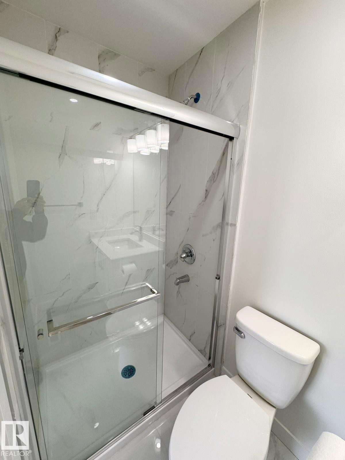 Contemporary bathroom featuring a glass-enclosed shower with white marble-look tile surround and chrome fixtures - 20 Hunt Road, Edmonton, AB - Indoor Photo Showing Bathroom