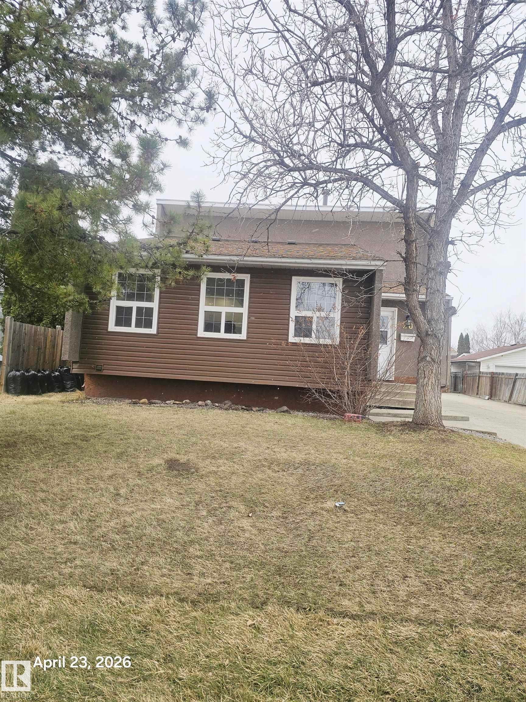 Brown horizontal siding exterior with white window frames and a sloped roofline - 20 Hunt Road, Edmonton, AB - Outdoor