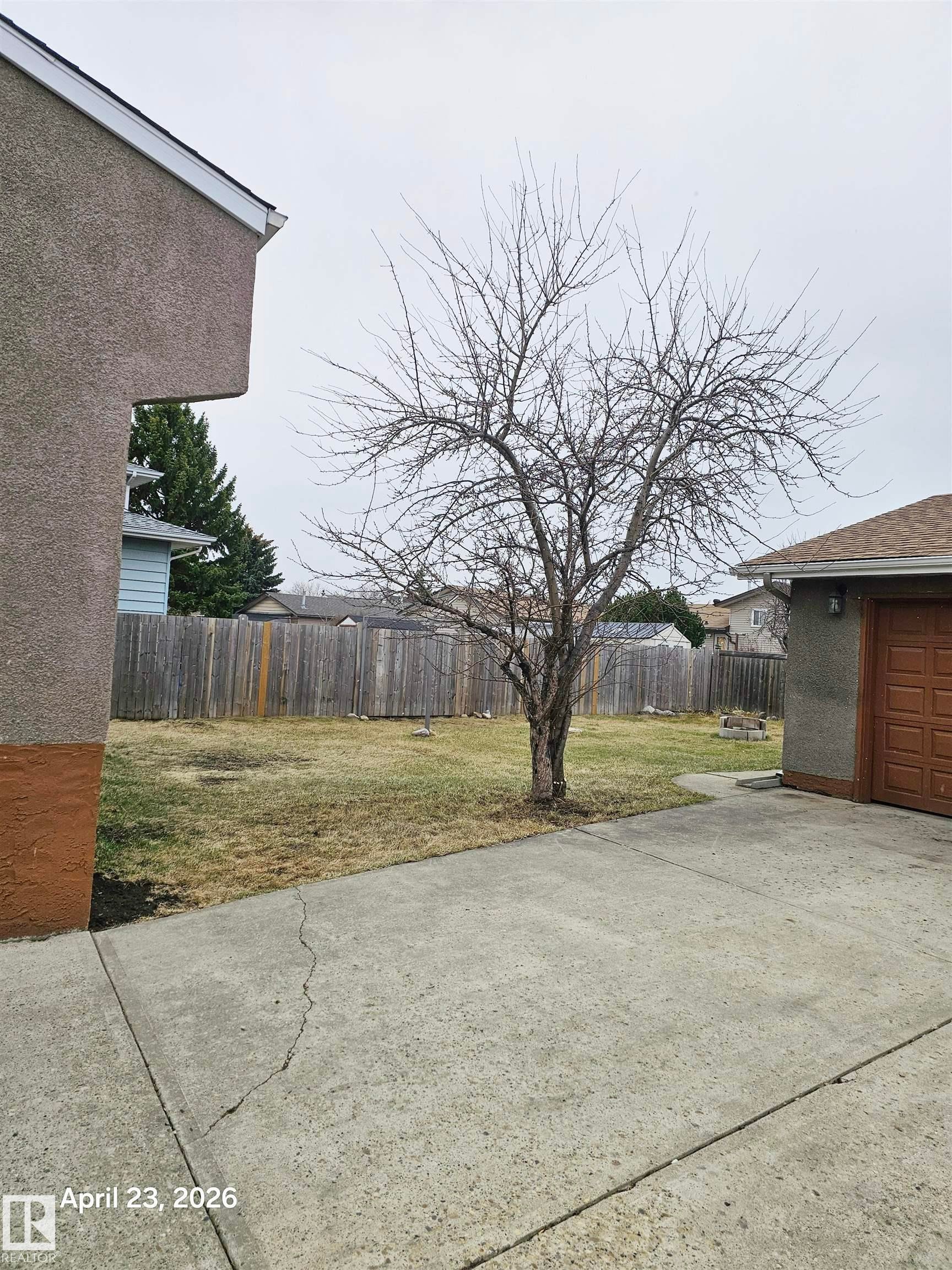 Expansive concrete driveway with a detached garage featuring a paneled door - 20 Hunt Road, Edmonton, AB - Outdoor