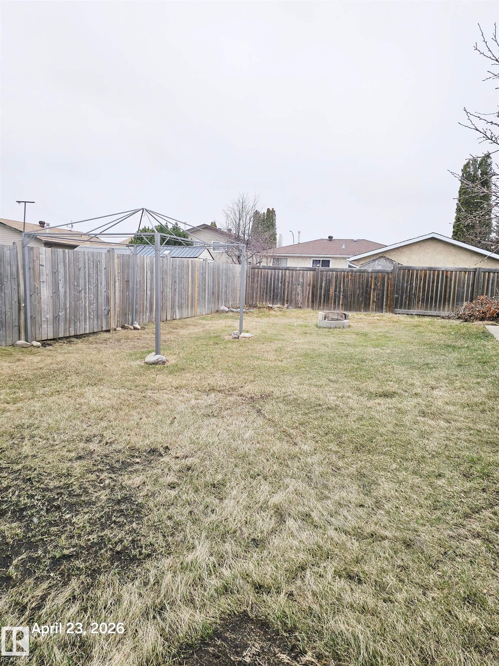 Expansive backyard featuring a full perimeter wooden fence, a clothesline, and a built-in fire pit - 20 Hunt Road, Edmonton, AB - Outdoor