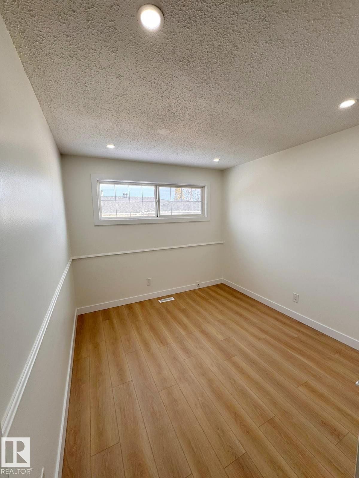 Room featuring wood-finish flooring, white baseboards, and a chair rail - 20 Hunt Road, Edmonton, AB - Indoor Photo Showing Other Room