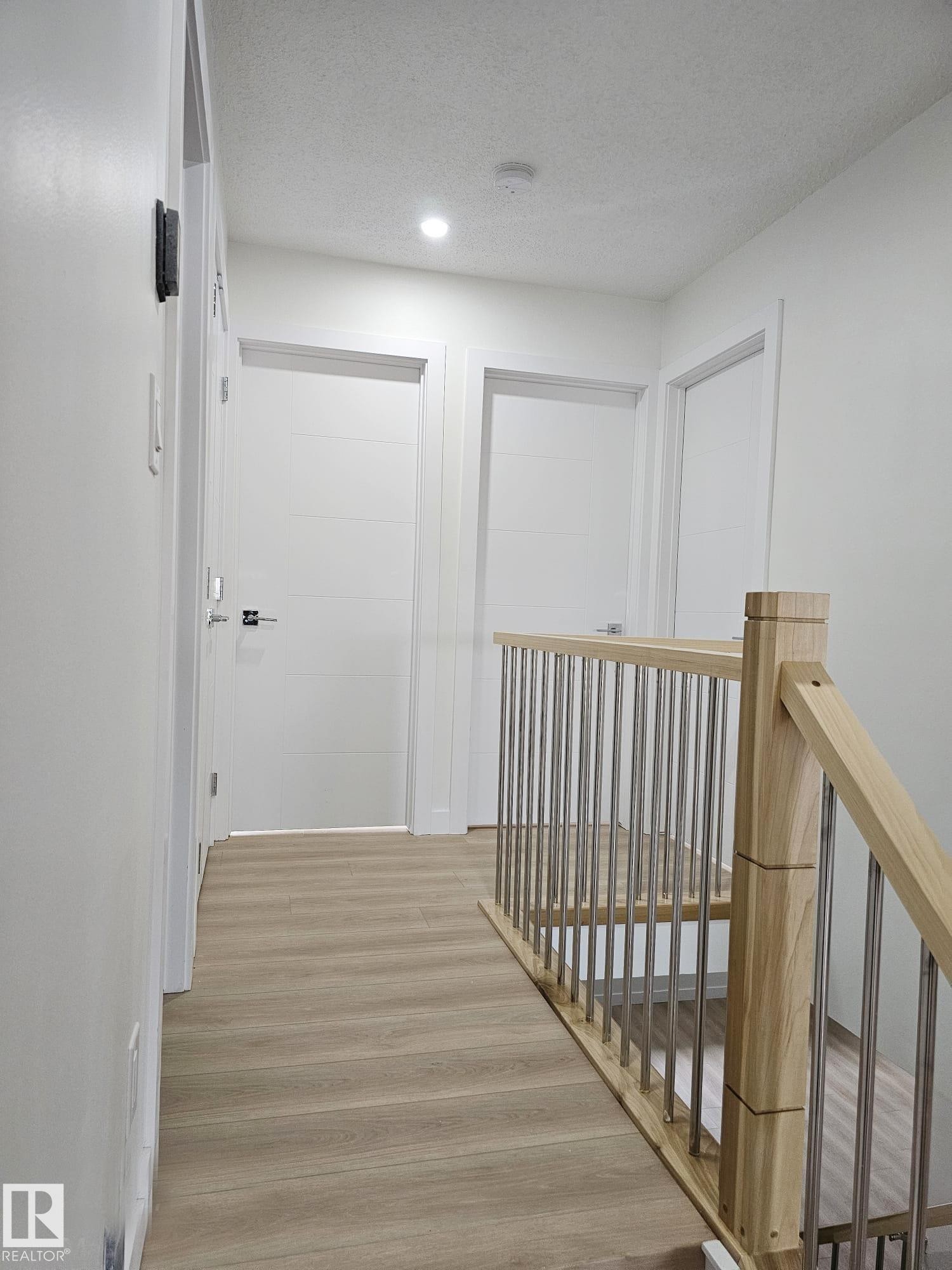 Upper-level hallway featuring wood-finish flooring, recessed lighting, and a contemporary wood and metal railing - 20 Hunt Road, Edmonton, AB - Indoor Photo Showing Other Room