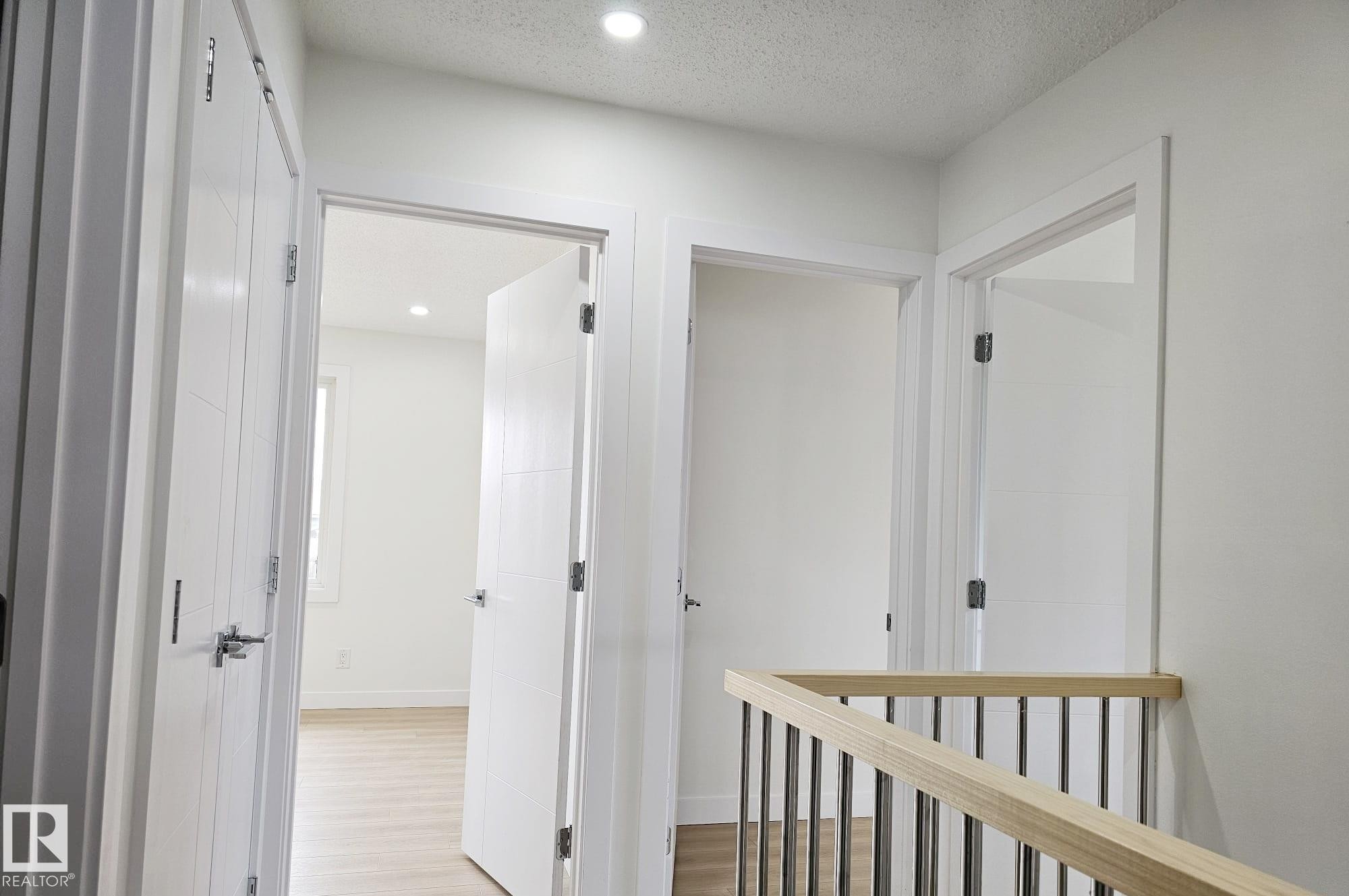 Bright hallway featuring a light wood railing with metal balusters, recessed lighting, and white paneled doors with chrome hardware - 20 Hunt Road, Edmonton, AB - Indoor Photo Showing Other Room