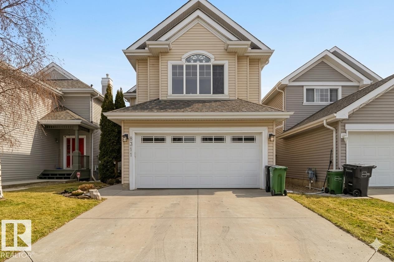 Two-story home featuring light-colored siding, a prominent two-car garage, and a concrete driveway - 8311 11 Avenue, Edmonton, AB - Outdoor With Facade
