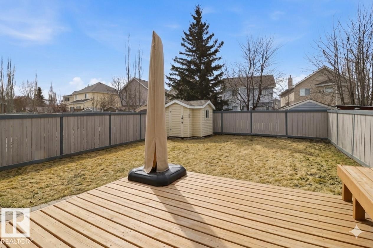Expansive backyard featuring a large wooden deck, full perimeter fencing, and a built-in storage shed - 8311 11 Avenue, Edmonton, AB - Outdoor With Deck Patio Veranda
