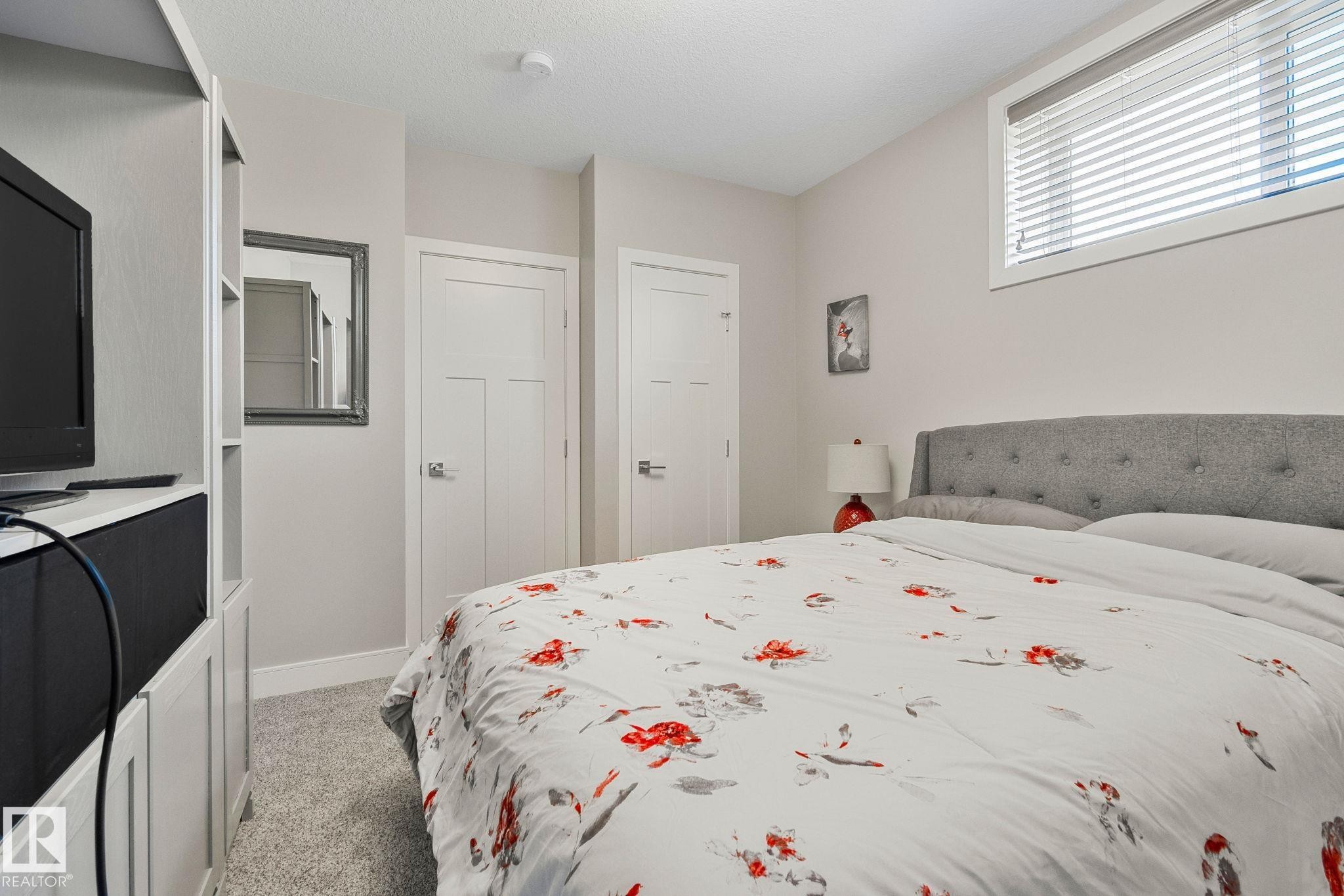 Carpeted room featuring a built-in media cabinet, two solid core interior doors, a window with horizontal blinds, and recessed lighting - 67 Enchanted Way Nw, St. Albert, AB - Indoor Photo Showing Bedroom