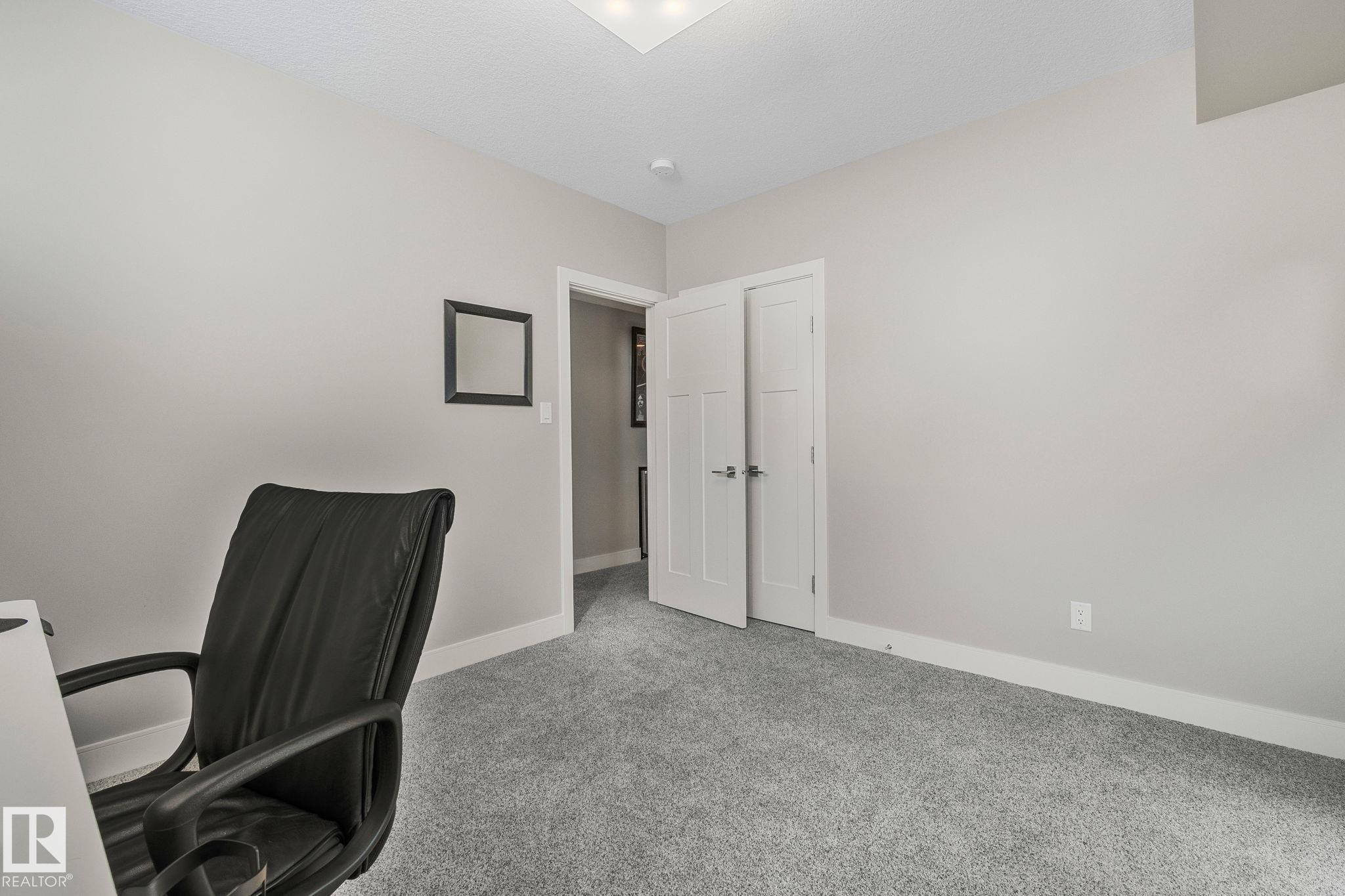 Neutral-toned interior room featuring light gray walls, plush gray carpeting, white trim, and a white paneled door - 67 Enchanted Way Nw, St. Albert, AB - Indoor Photo Showing Other Room