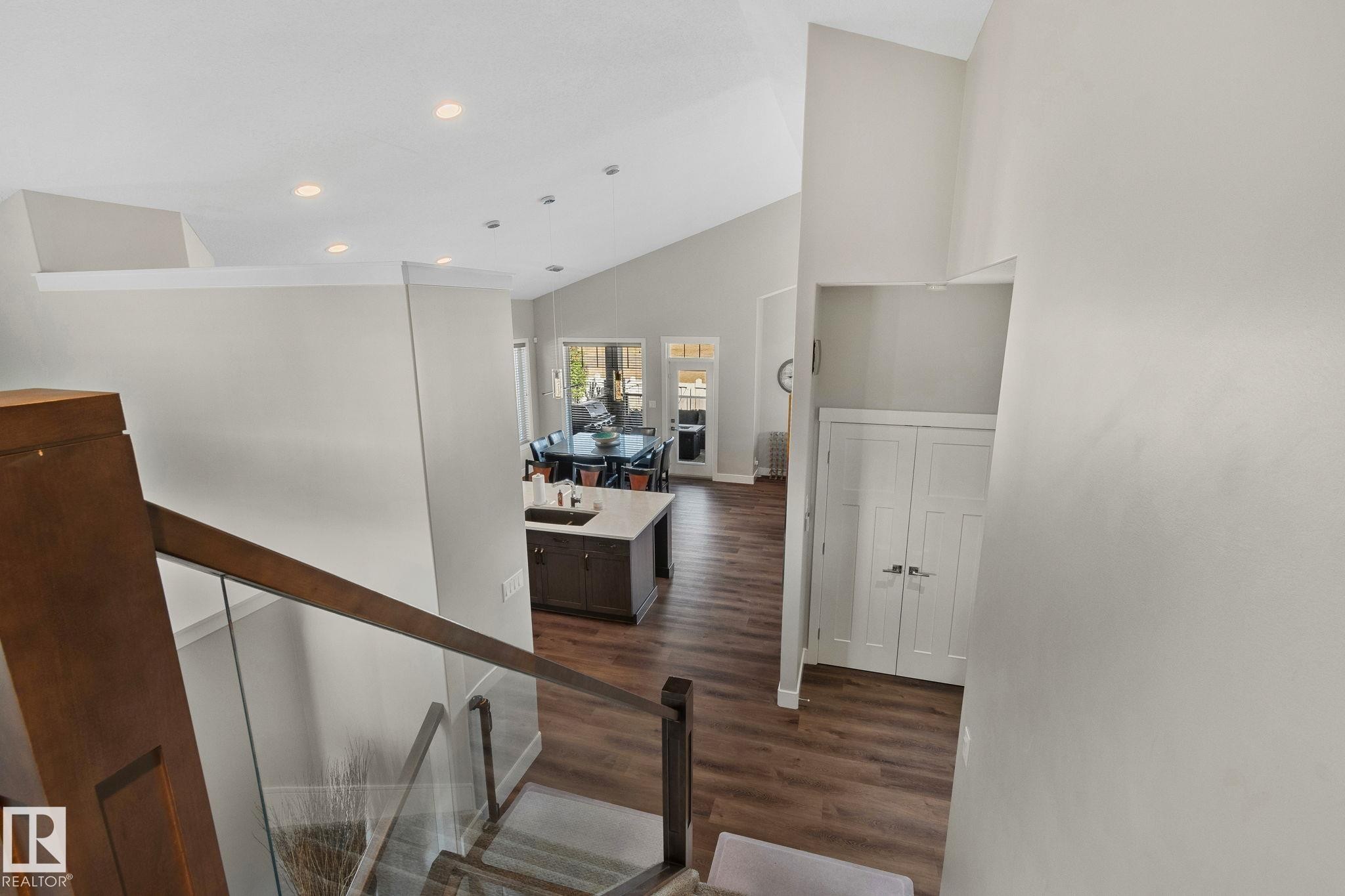 Modern staircase with glass panel railing and wood-finish flooring - 67 Enchanted Way Nw, St. Albert, AB - Indoor Photo Showing Other Room