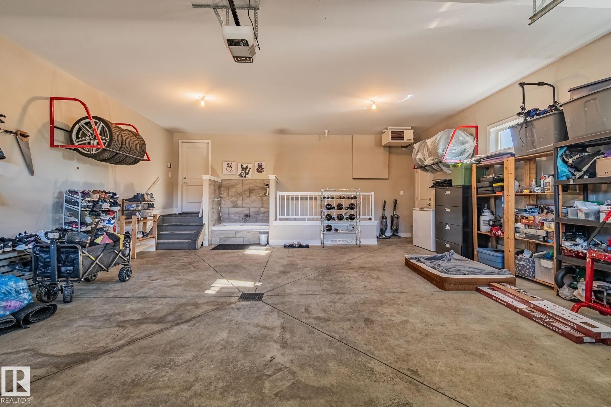 Spacious garage featuring a concrete floor, overhead lighting, and an overhead garage door opener - 67 Enchanted Way Nw, St. Albert, AB - Indoor Photo Showing Garage