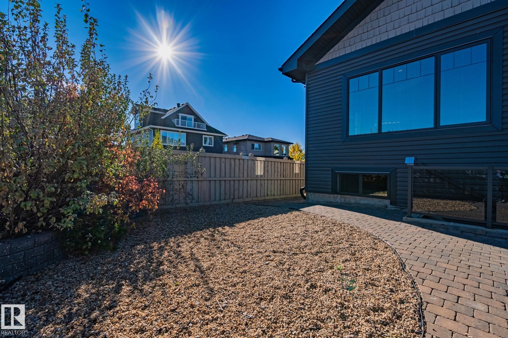 Exterior featuring dark siding, multiple large windows, and a glass-paneled deck railing - 67 Enchanted Way Nw, St. Albert, AB - Outdoor