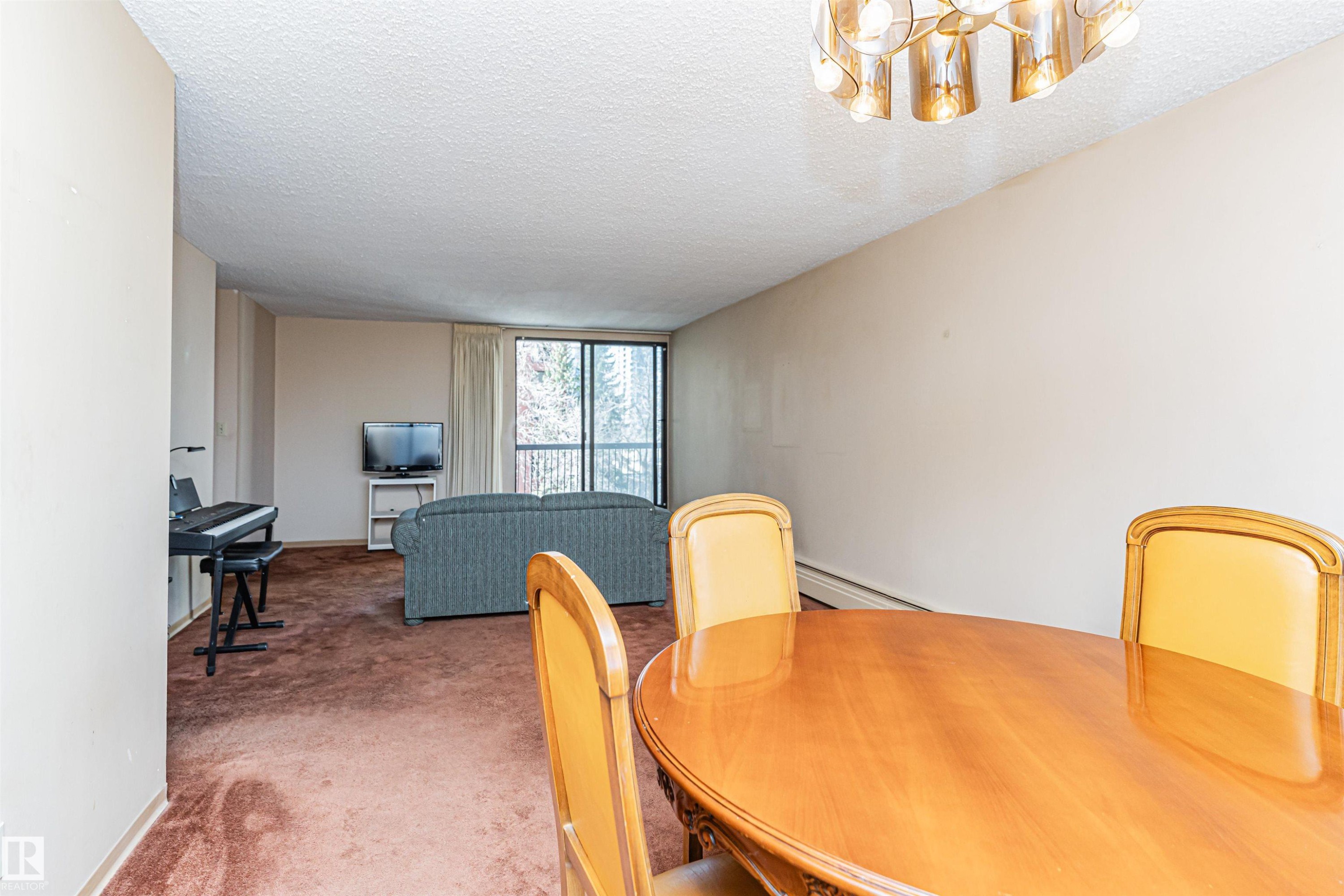 Dining area with an oval wood-finish table and a contemporary ceiling light fixture - 407 10045 118 Street, Edmonton, AB - Indoor