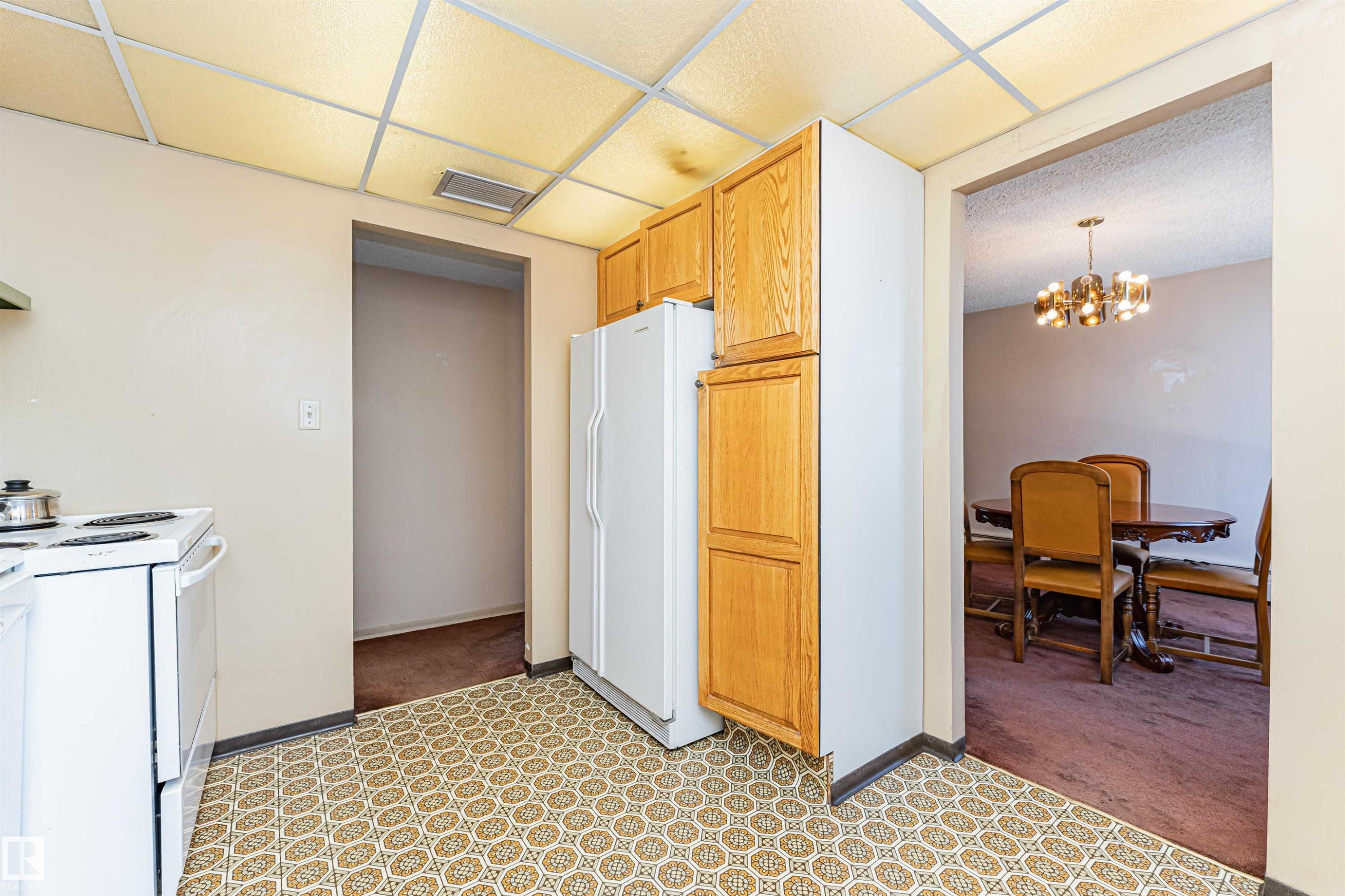 Kitchen featuring patterned floor tiles, white appliances, and wood-finish cabinetry - 407 10045 118 Street, Edmonton, AB - Indoor Photo Showing Kitchen