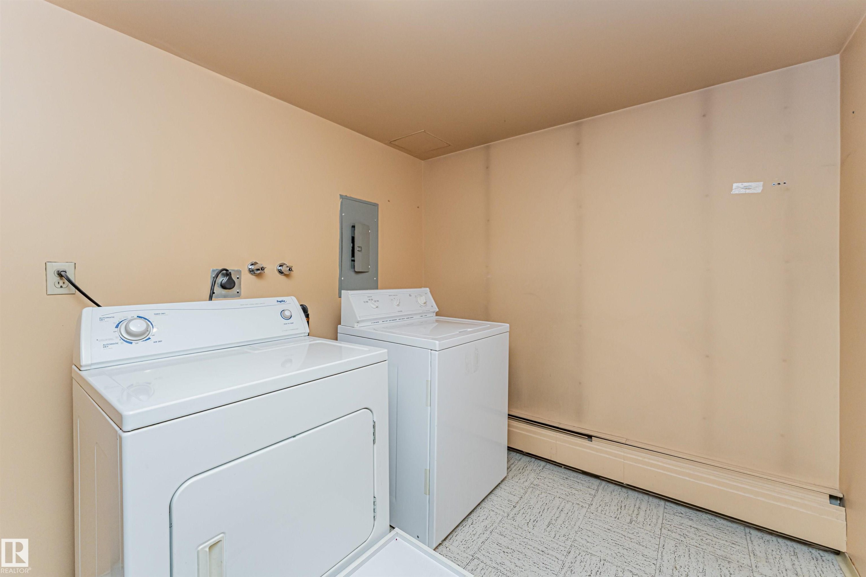 Dedicated laundry area featuring a washer and dryer, vinyl flooring, and baseboard heating - 407 10045 118 Street, Edmonton, AB - Indoor Photo Showing Laundry Room