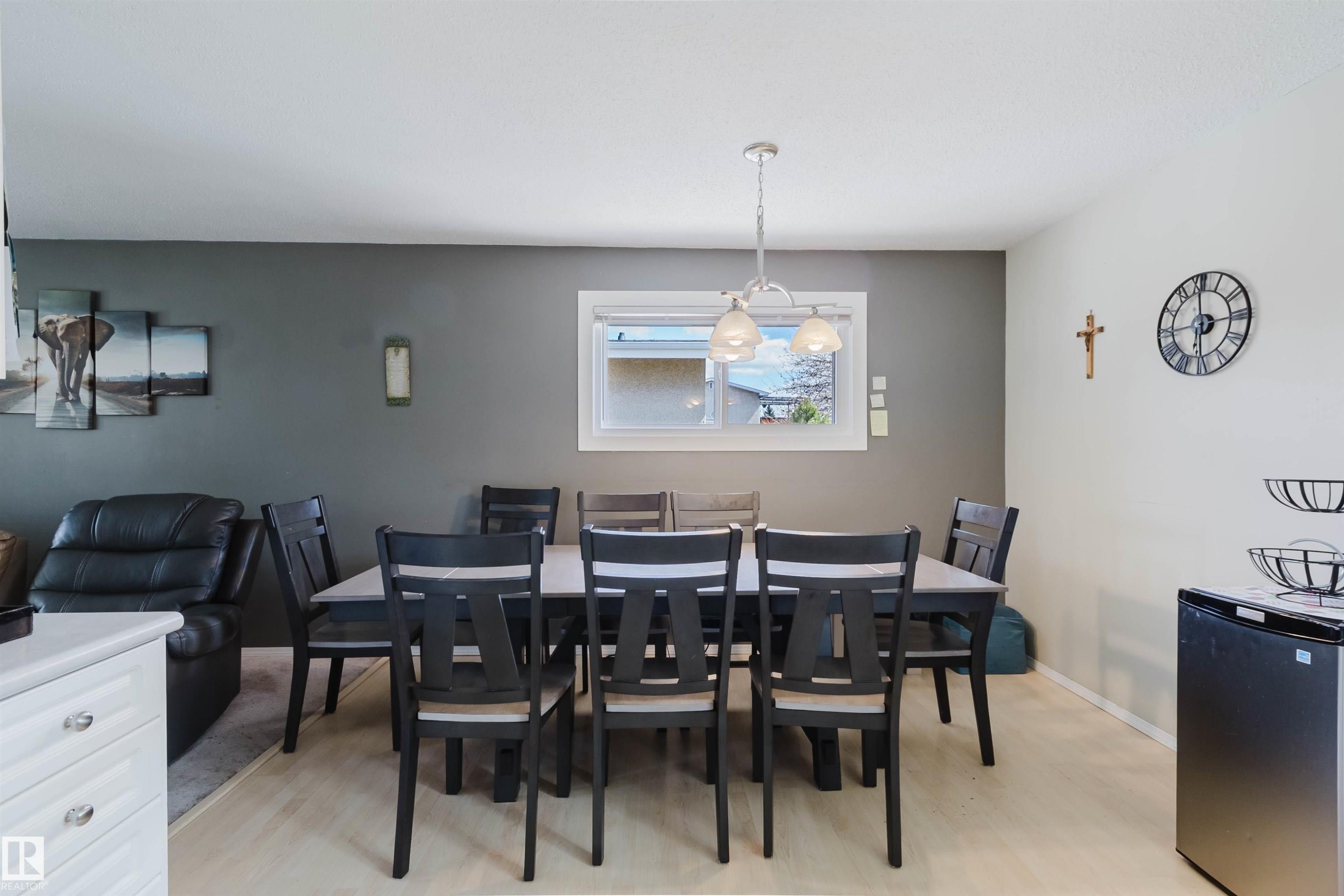 Dining area featuring a contemporary chandelier, light wood-finish flooring, and a window with white trim - 10519 36A Avenue, Edmonton, AB - Indoor Photo Showing Dining Room