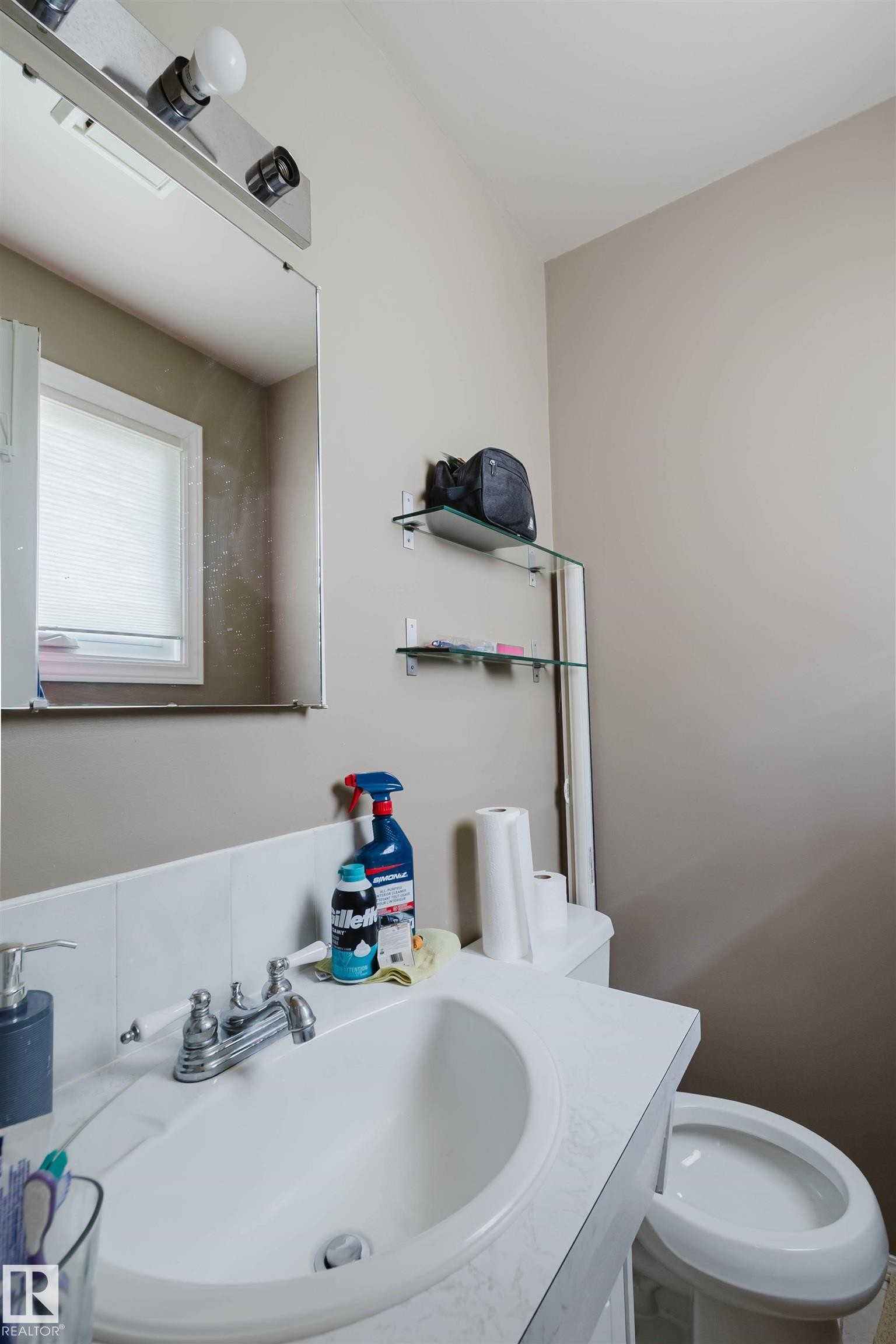 Bathroom vanity with integrated sink, chrome faucet, and mirrored medicine cabinet - 10519 36A Avenue, Edmonton, AB - Indoor Photo Showing Bathroom