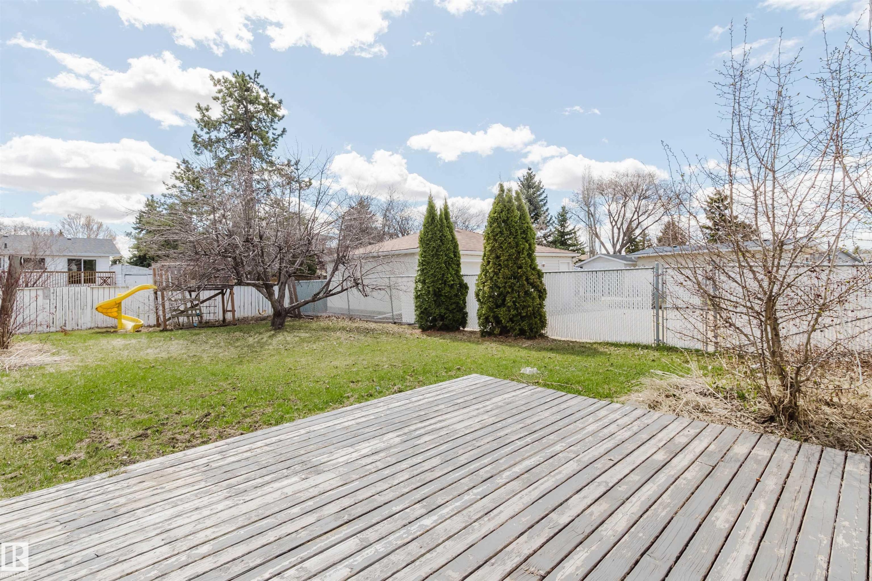Expansive backyard featuring a wood deck, green lawn, and mature trees - 10519 36A Avenue, Edmonton, AB - Outdoor