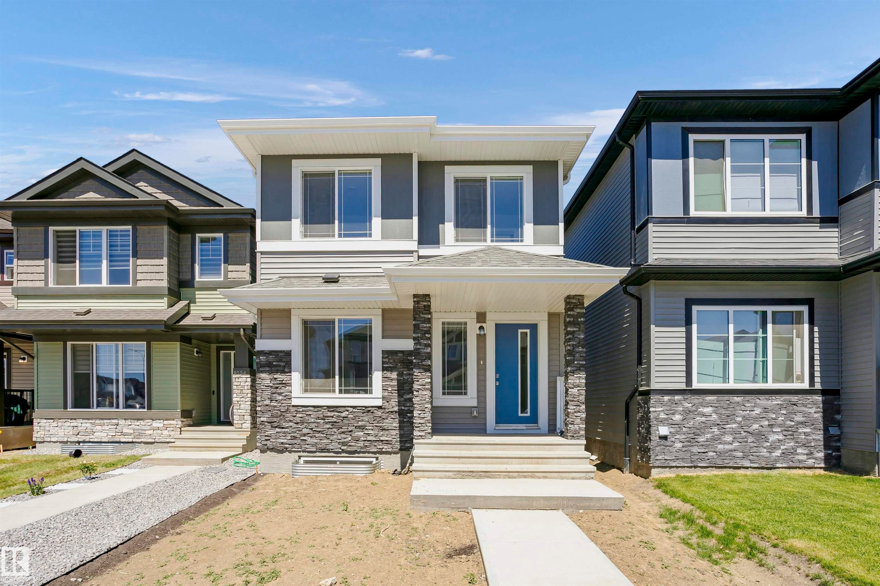 Modern facade featuring a blue entry door, stone veneer accents, and multiple windows - 9552 Carson Bend Bend, Edmonton, AB - Outdoor With Facade