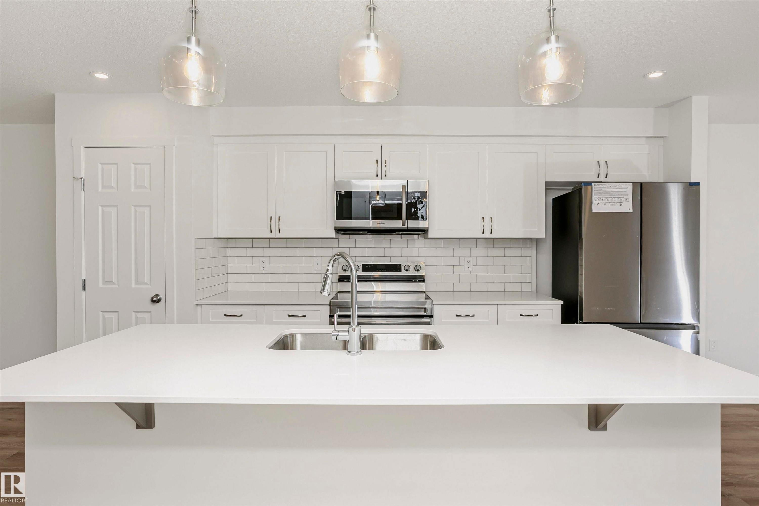 Spacious kitchen island featuring a dual-basin undermount sink and modern faucet - 9552 Carson Bend Bend, Edmonton, AB - Indoor Photo Showing Kitchen With Double Sink With Upgraded Kitchen
