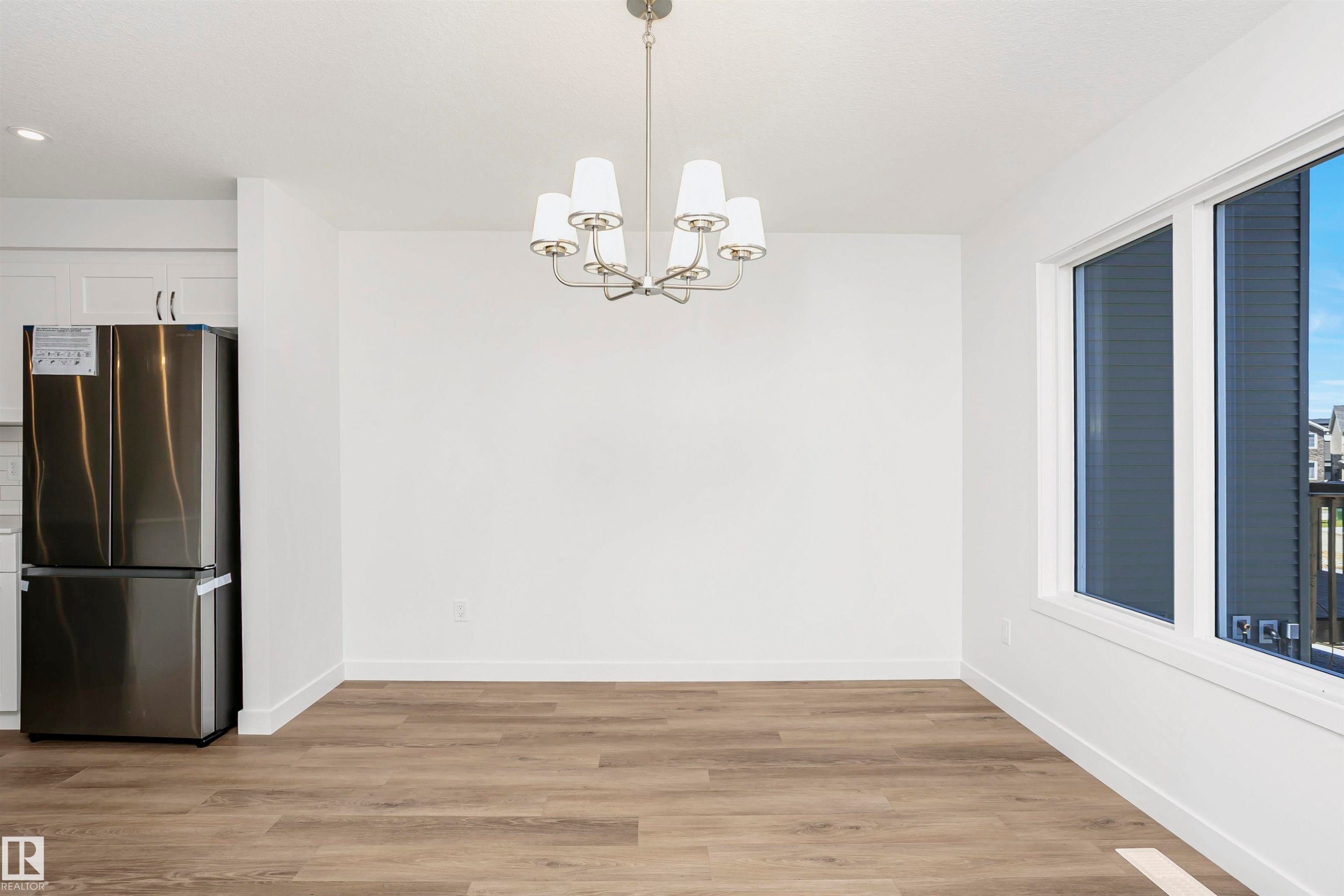 Spacious room featuring wood-finish flooring, white walls, and a multi-light chandelier - 9552 Carson Bend Bend, Edmonton, AB - Indoor Photo Showing Other Room