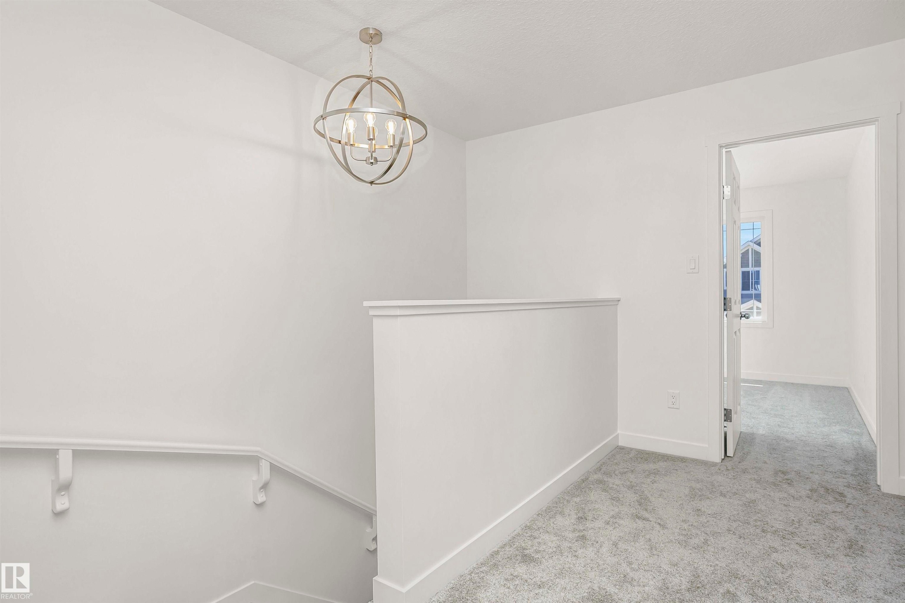 Bright landing area featuring a contemporary spherical chandelier and light grey carpeting - 9552 Carson Bend Bend, Edmonton, AB - Indoor Photo Showing Other Room