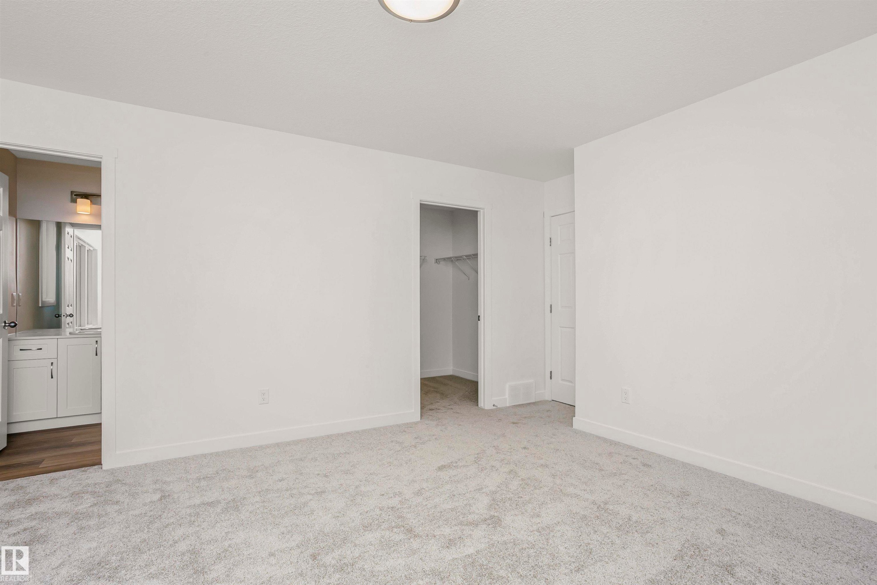 Plush grey carpeting and a neutral color palette define this room, featuring a built-in closet with shelving and a contemporary ceiling fixture - 9552 Carson Bend Bend, Edmonton, AB - Indoor Photo Showing Other Room