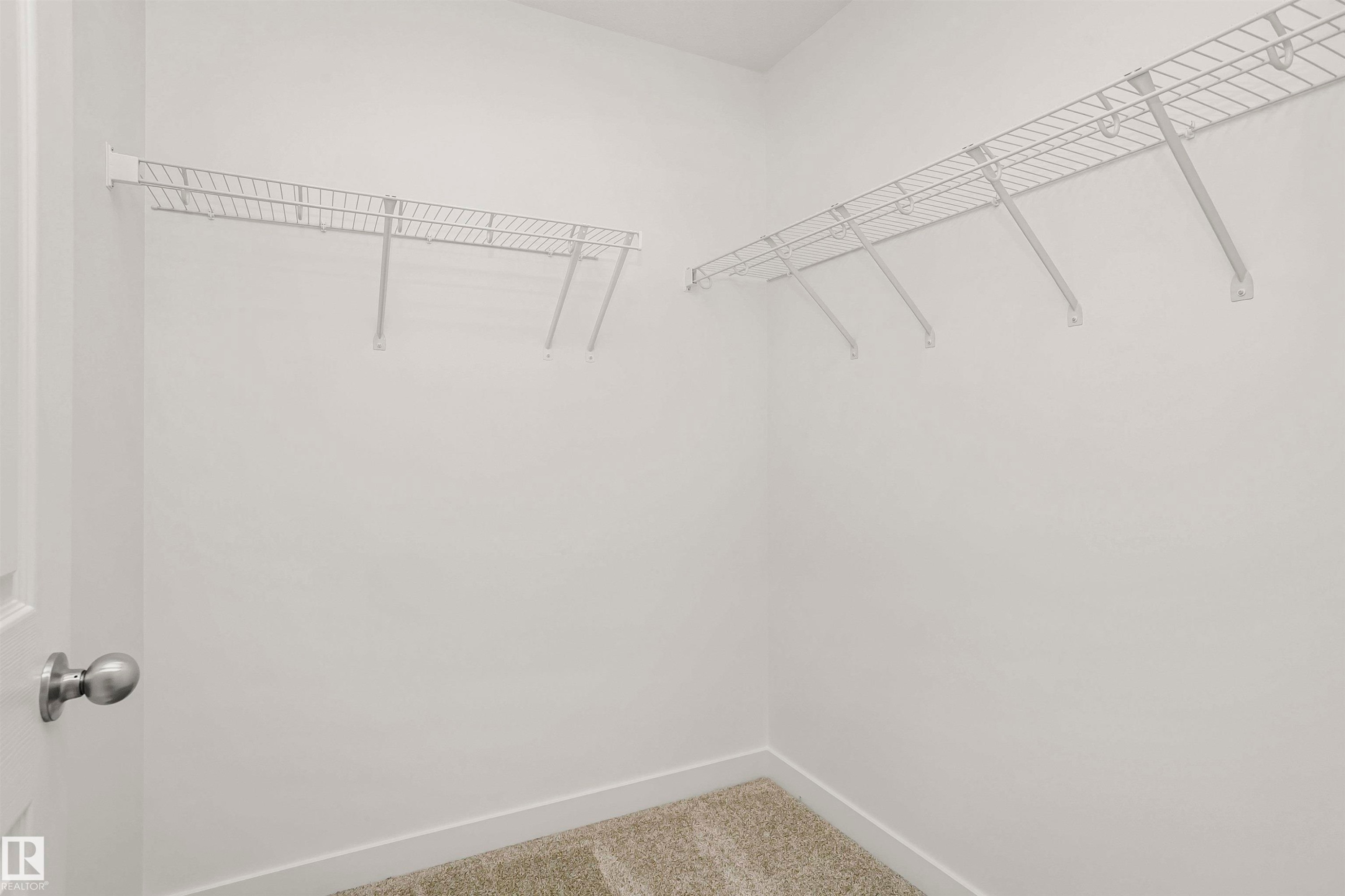Walk-in closet featuring light beige carpeting, white wire shelving, and crisp white walls - 9552 Carson Bend Bend, Edmonton, AB - Indoor With Storage