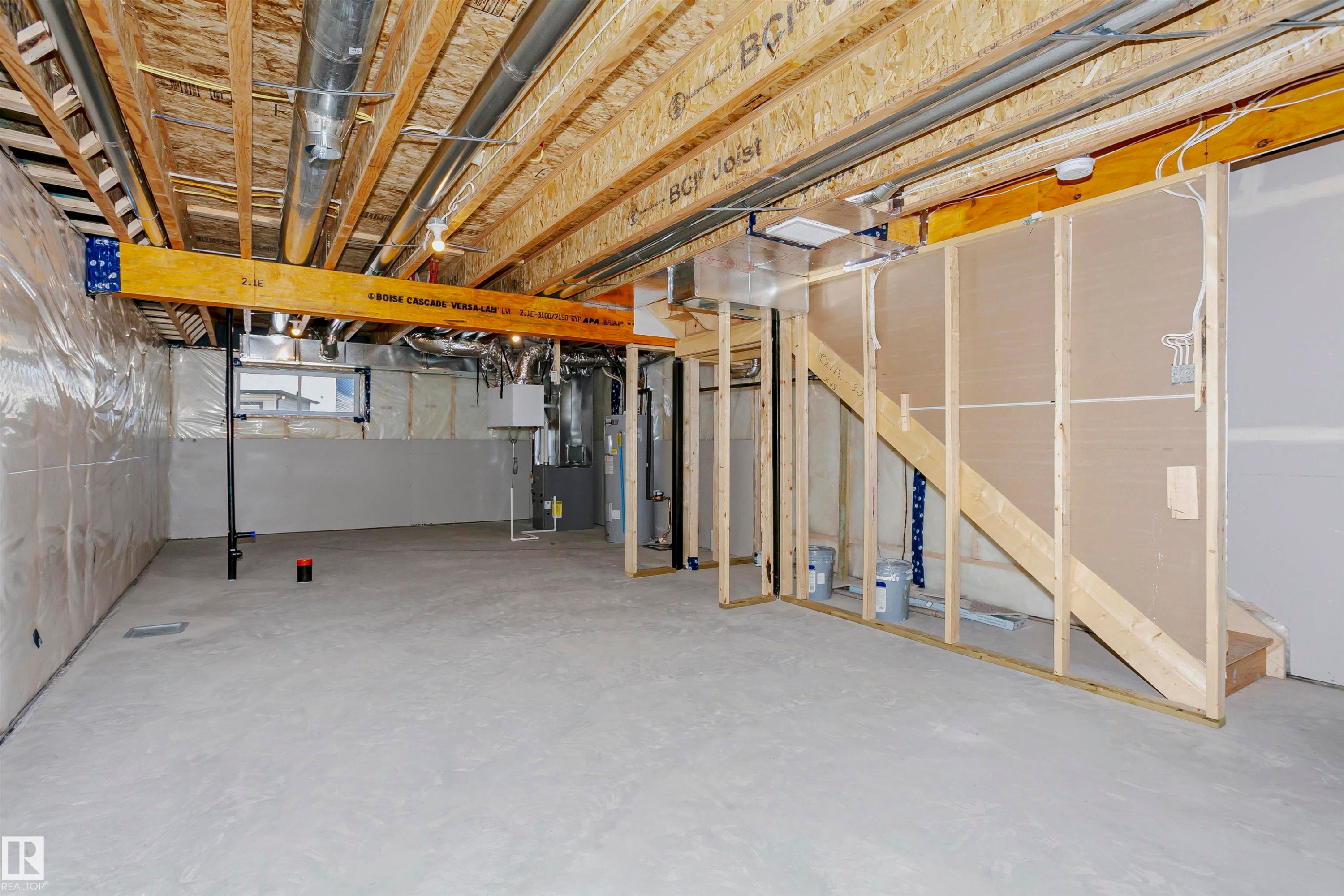 Unfinished basement offering substantial expansion potential, featuring exposed ceiling joists, concrete flooring, and a framed staircase - 9552 Carson Bend Bend, Edmonton, AB - Indoor Photo Showing Basement