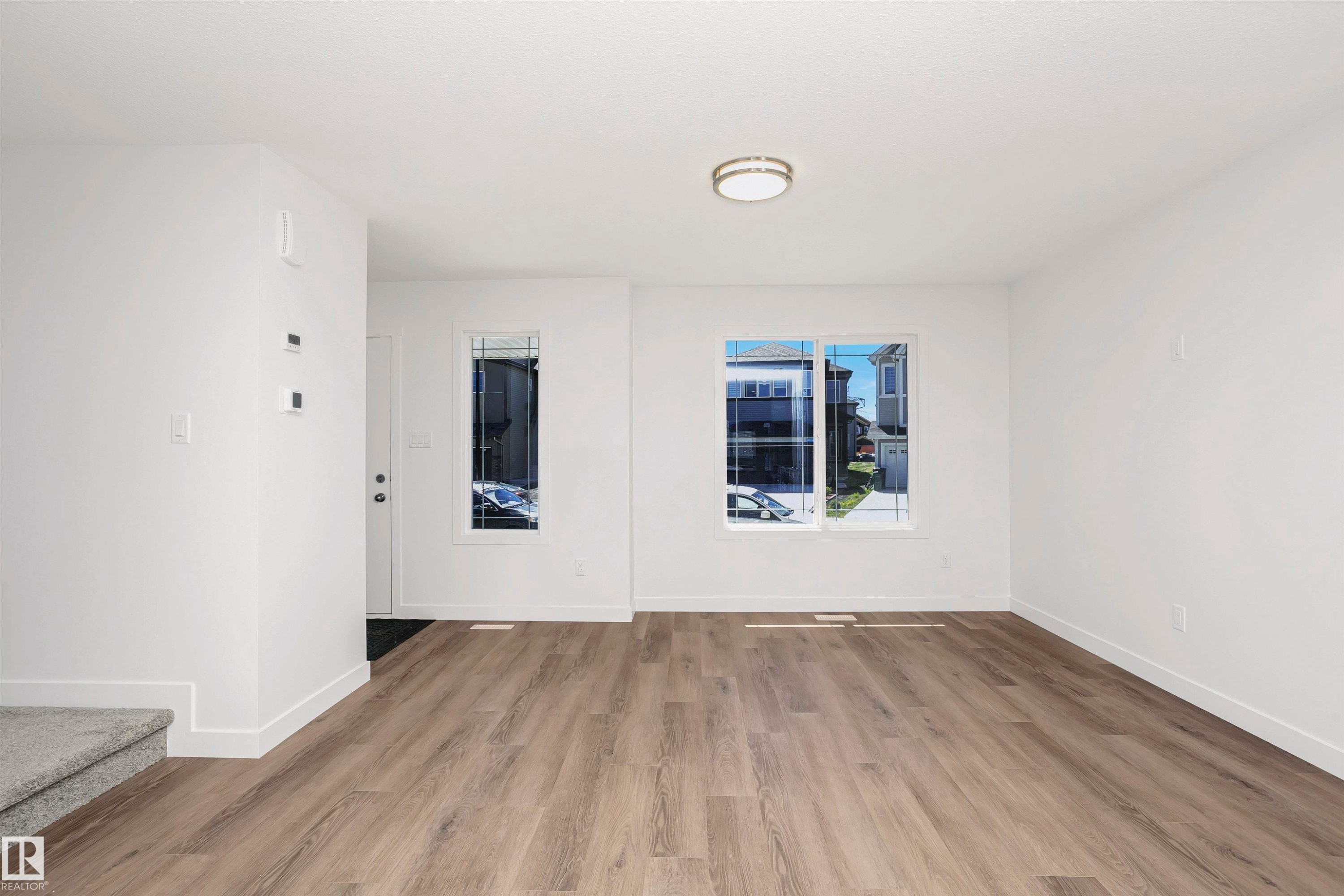 Open concept living area featuring contemporary wood-finish flooring, white walls, and a recessed ceiling light fixture - 9552 Carson Bend Bend, Edmonton, AB - Indoor Photo Showing Other Room