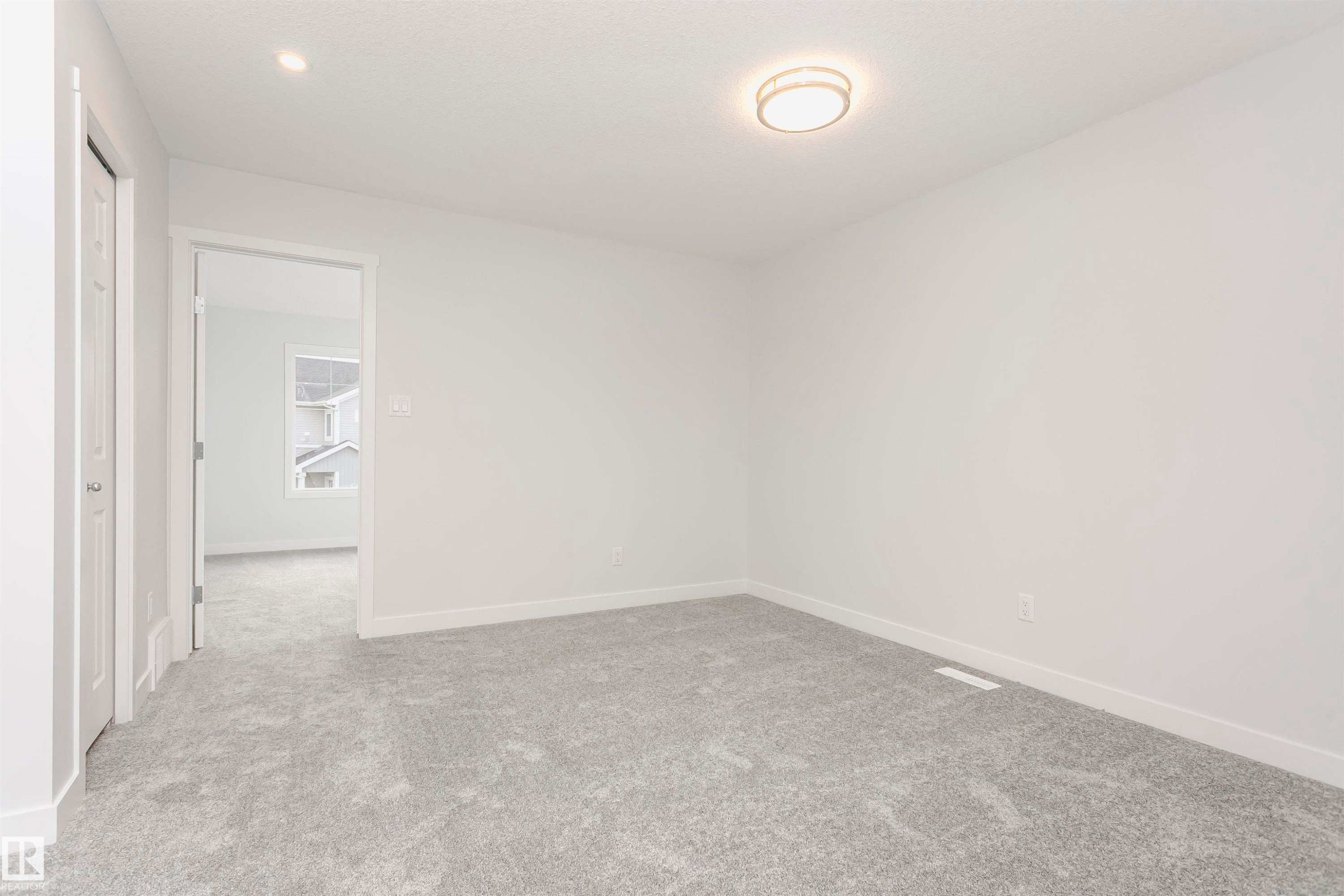 Spacious room featuring light gray carpeting, white painted walls, white trim, a flush mount ceiling light, and a recessed ceiling light - 9564 Carson Bend Bend, Edmonton, AB - Indoor Photo Showing Other Room