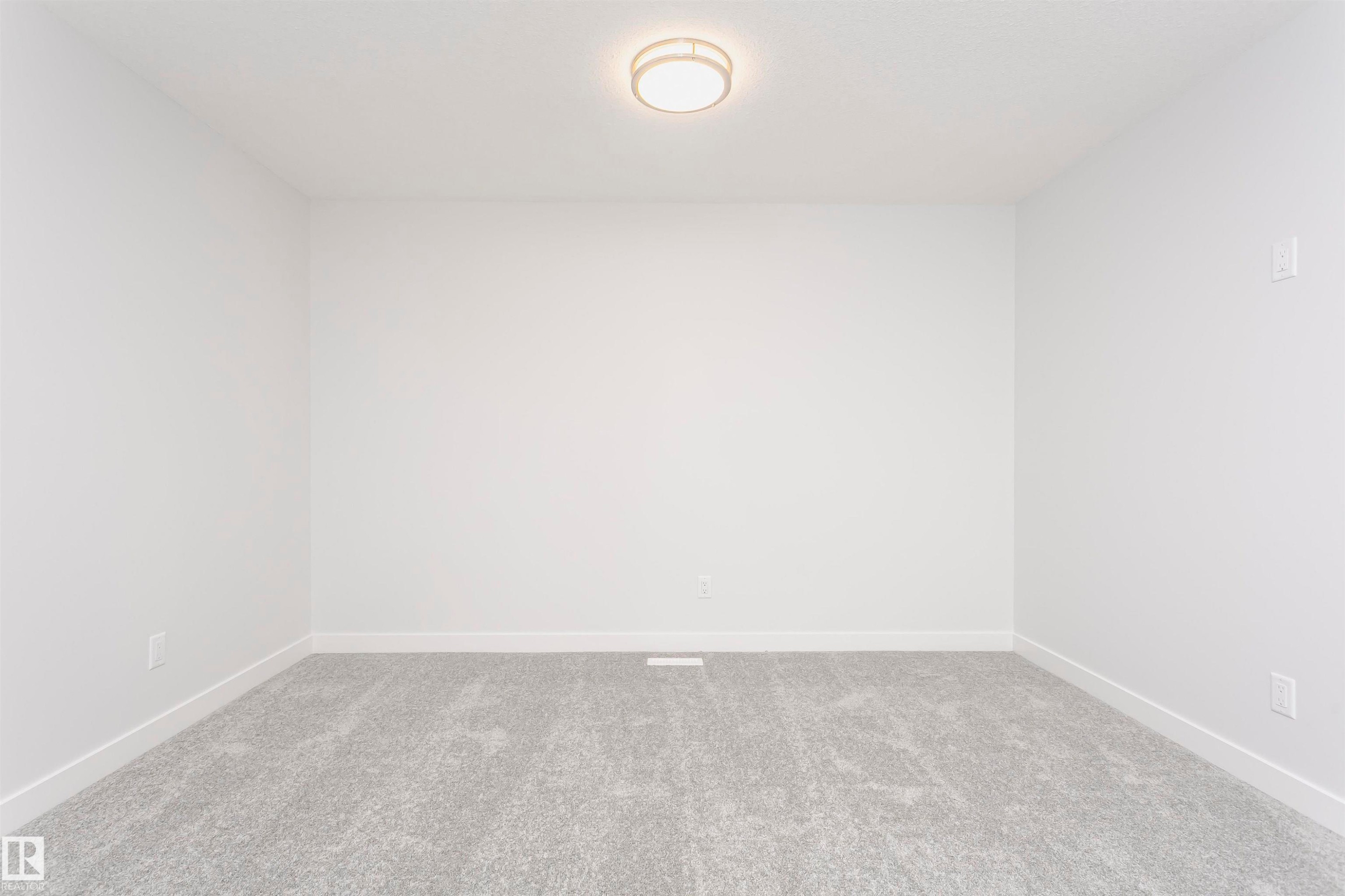 Neutral white walls featuring a contemporary flush-mount ceiling light, light gray carpeting, and white baseboards - 9564 Carson Bend Bend, Edmonton, AB - Indoor Photo Showing Other Room