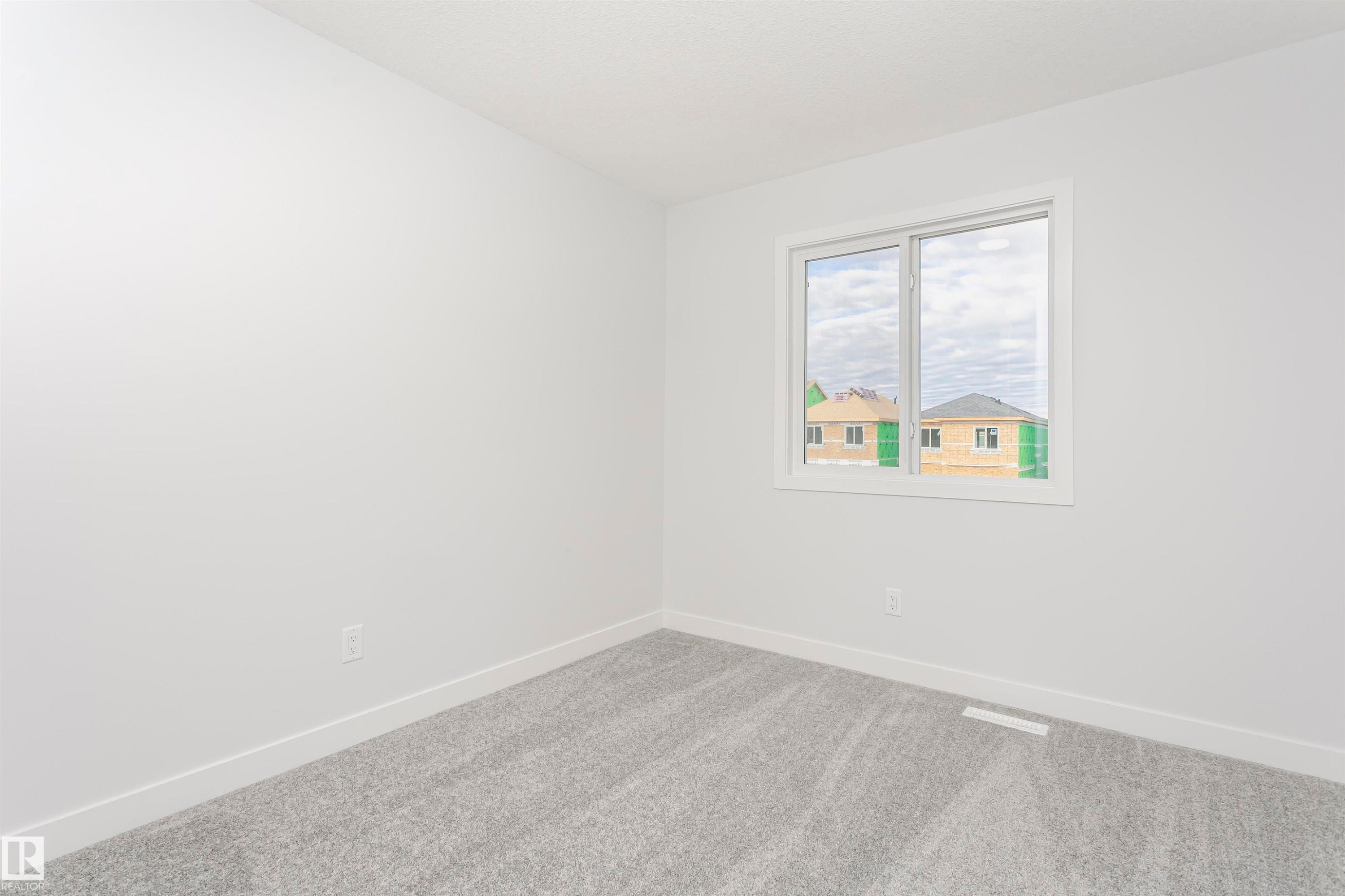 Bright room featuring a large window, plush gray carpet, and crisp white walls and trim - 9564 Carson Bend Bend, Edmonton, AB - Indoor Photo Showing Other Room