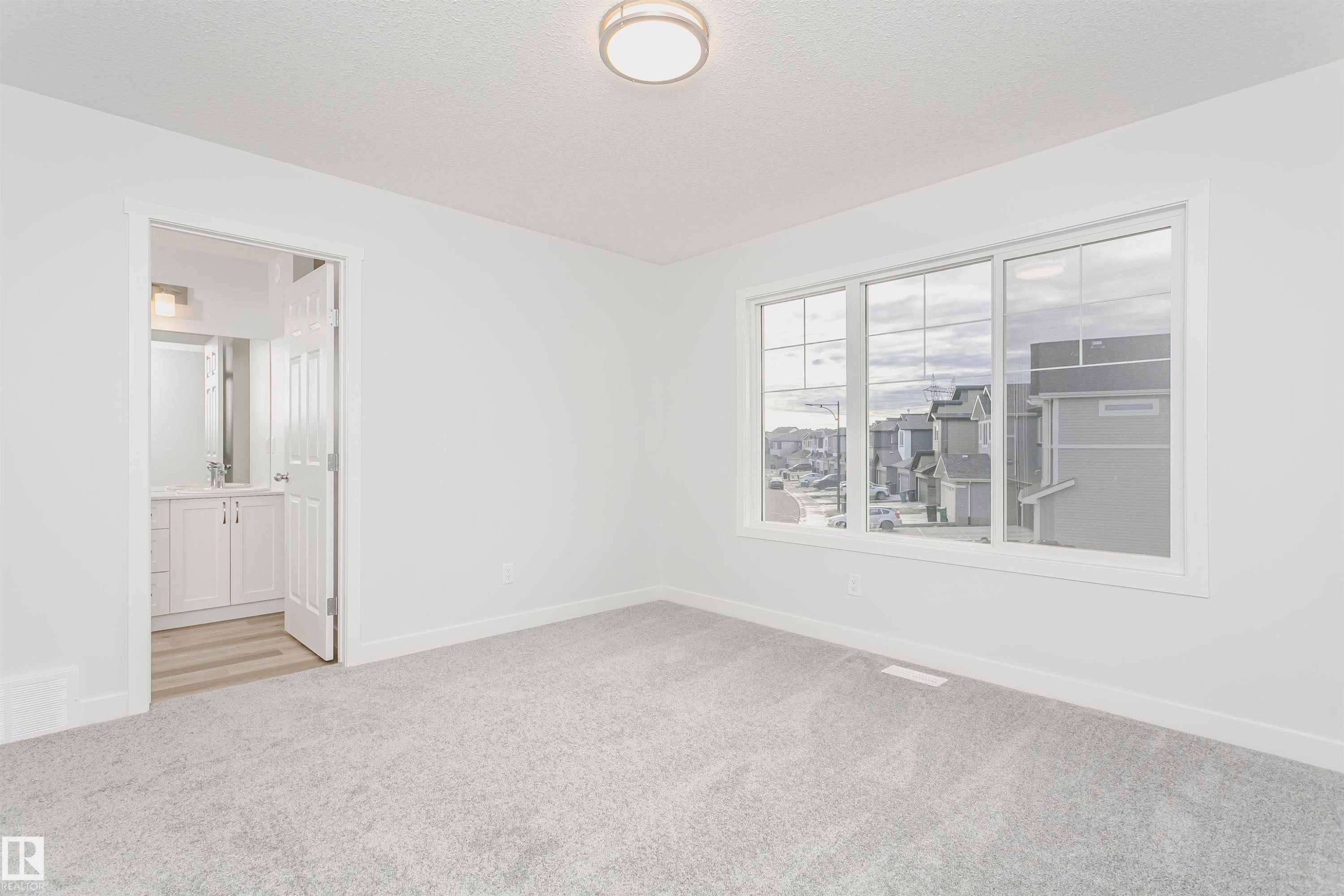 Plush gray carpeting throughout, featuring a three-panel window with white trim and a ceiling-mounted light fixture - 9564 Carson Bend Bend, Edmonton, AB - Indoor Photo Showing Other Room
