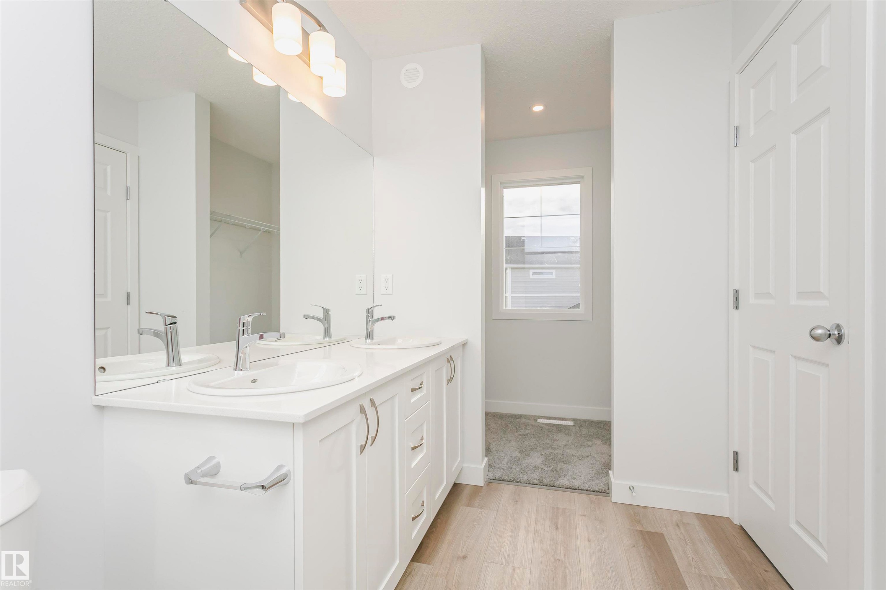 Double vanity with white cabinetry and chrome hardware, featuring dual undermount sinks and a wide mirror - 9564 Carson Bend Bend, Edmonton, AB - Indoor Photo Showing Bathroom
