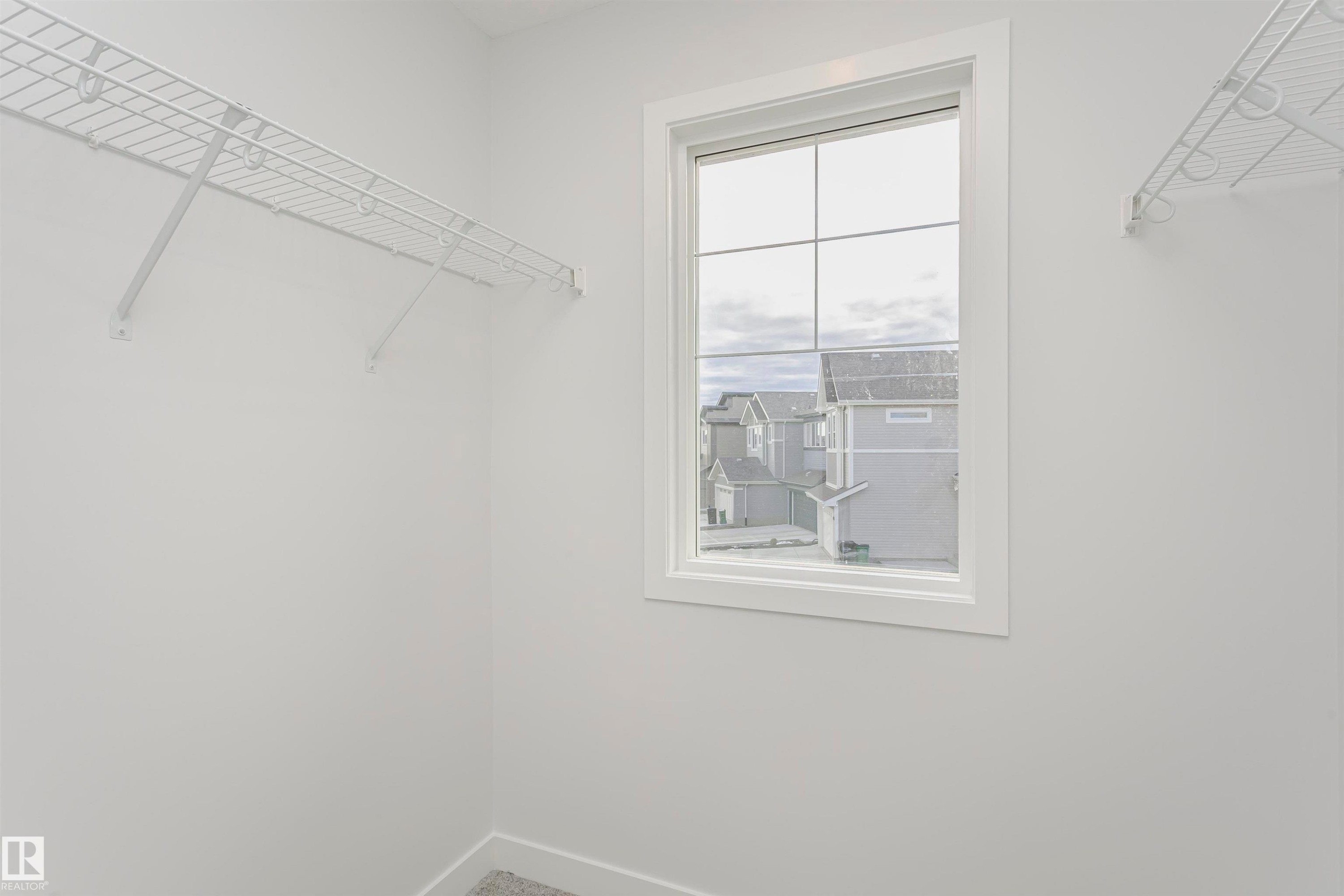Walk-in closet with grid wire shelving and a window featuring muntins and white trim - 9564 Carson Bend Bend, Edmonton, AB - Indoor With Storage