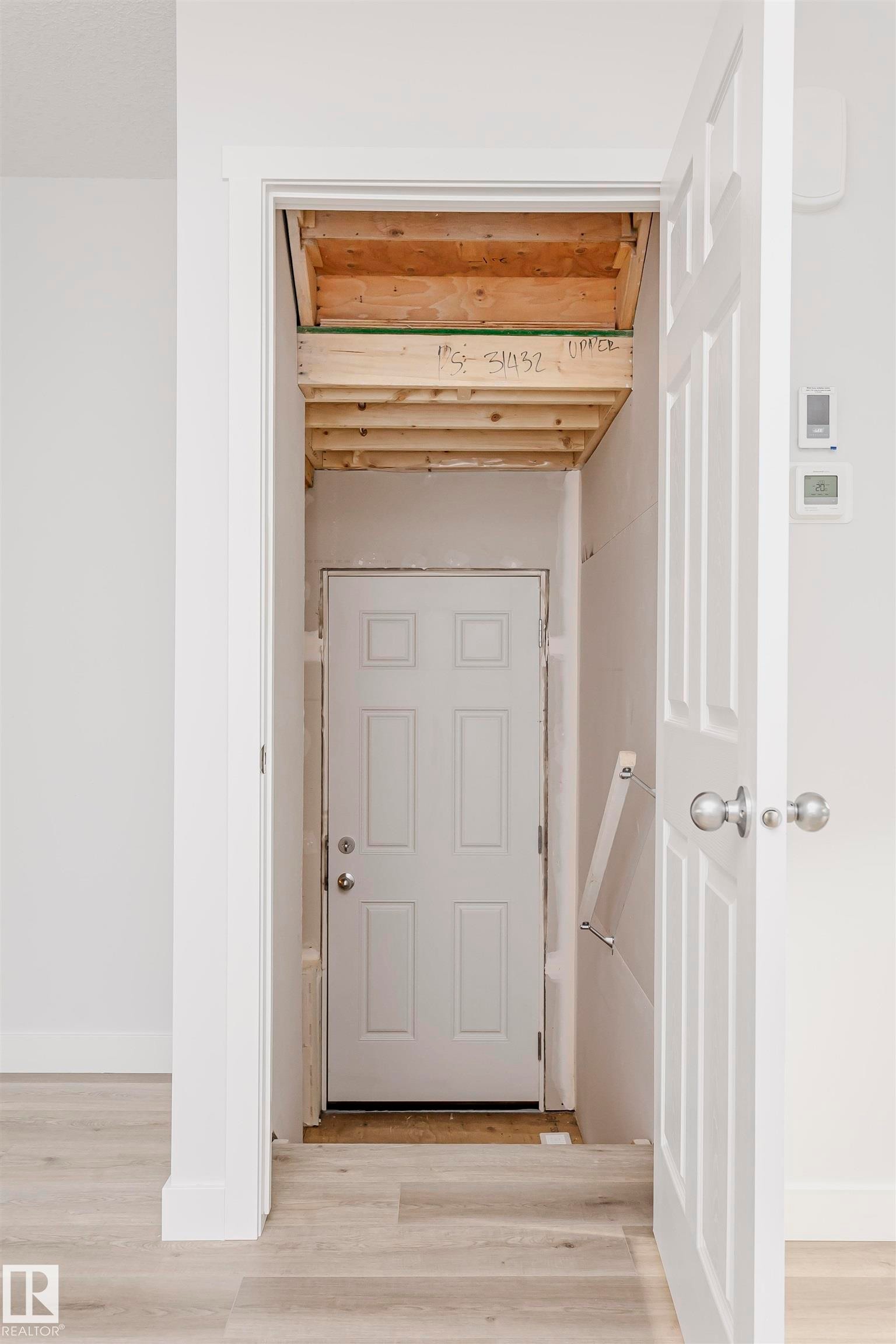 Light wood-finish flooring extending into an entry area with a white paneled door - 9564 Carson Bend Bend, Edmonton, AB - Indoor Photo Showing Other Room