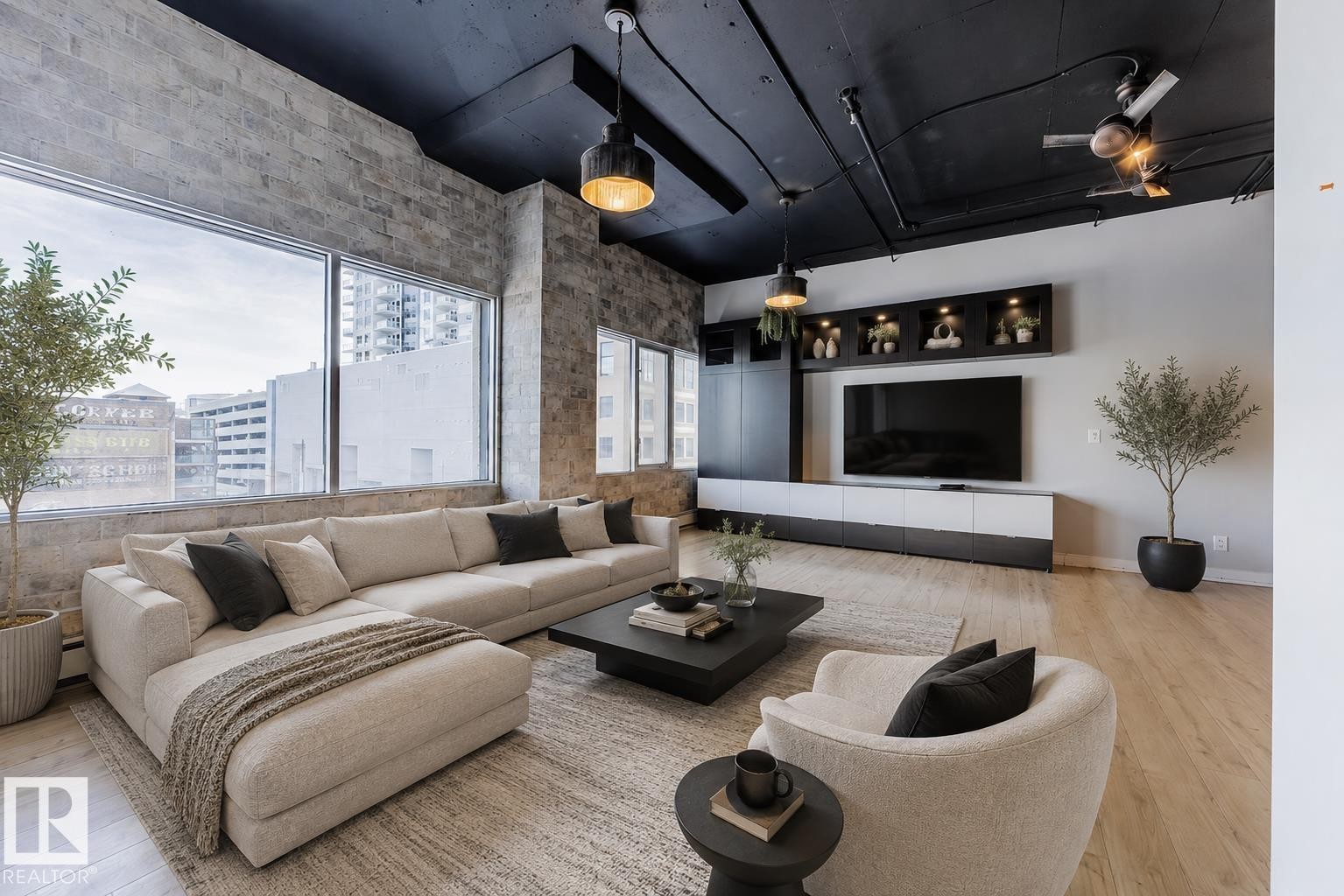 Open-concept living space featuring expansive windows, exposed brick accent walls, and wood-finish flooring - 303 10179 105 Street, Edmonton, AB