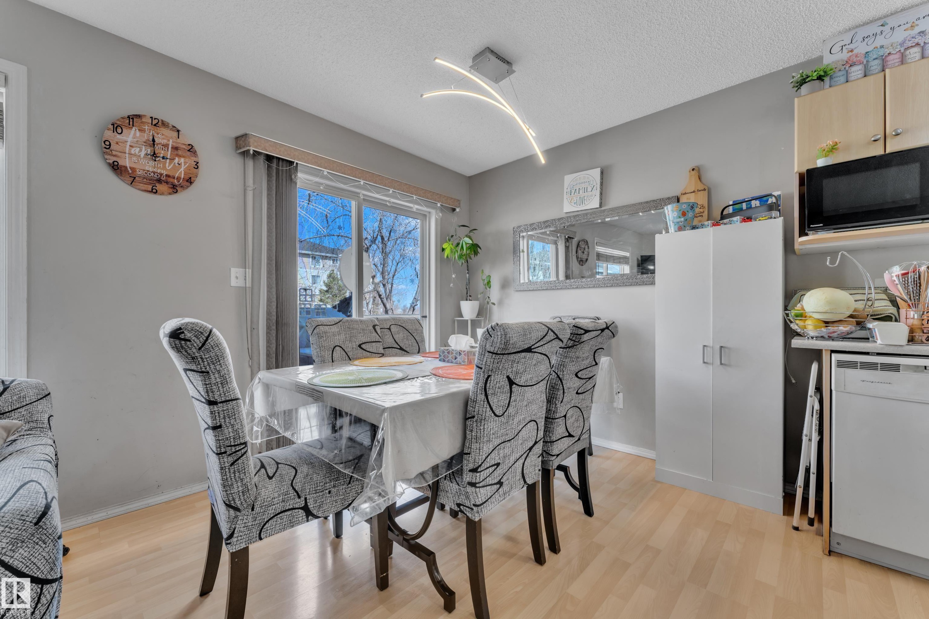 Dining area featuring wood-finish flooring and a contemporary linear light fixture - #64 4350 23 St Nw, Edmonton, AB - Indoor Photo Showing Dining Room