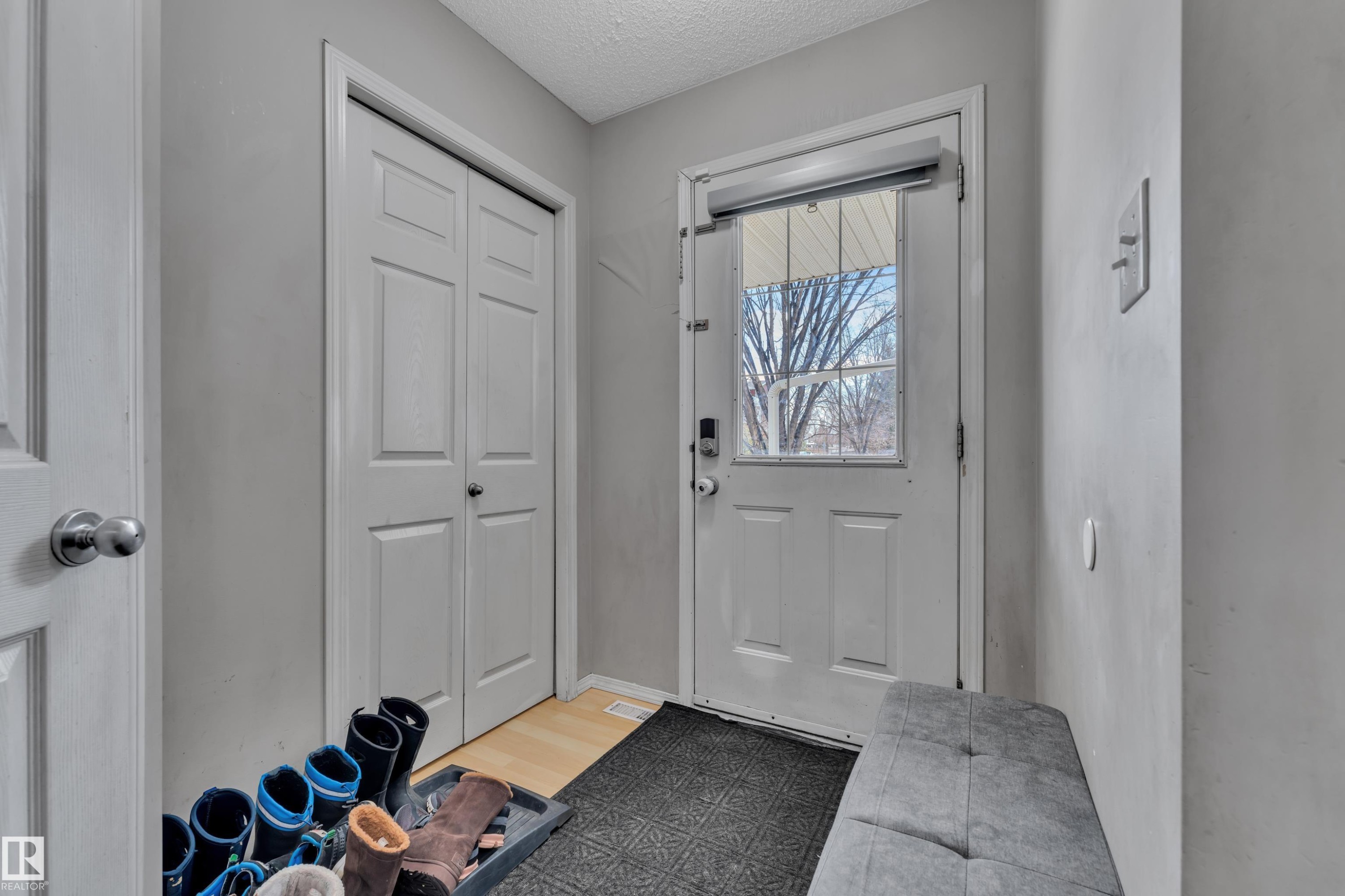 Front entry featuring a paneled door with glass insert, a built-in closet with bi-fold doors, and light gray wall paint - #64 4350 23 St Nw, Edmonton, AB - Indoor Photo Showing Other Room