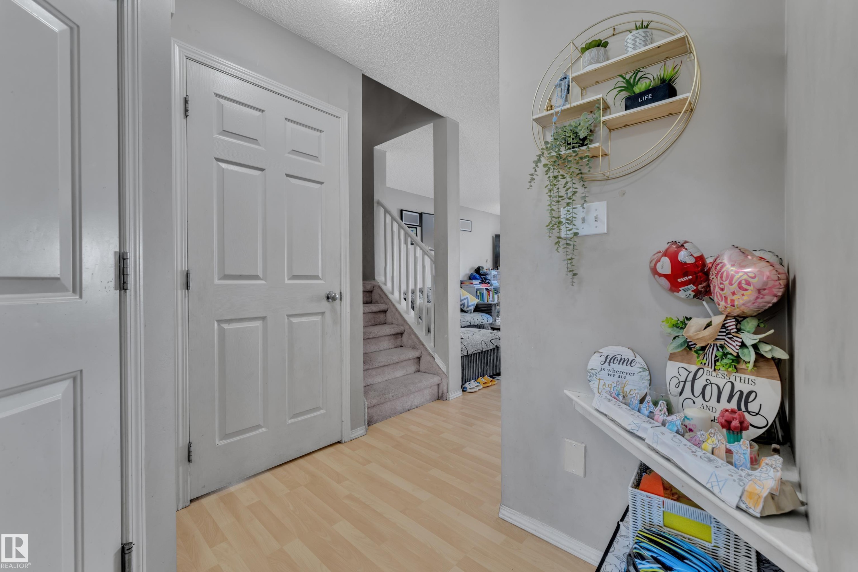 Hallway featuring light wood-finish flooring, white paneled doors, and a carpeted staircase with white railings - #64 4350 23 St Nw, Edmonton, AB - Indoor Photo Showing Other Room