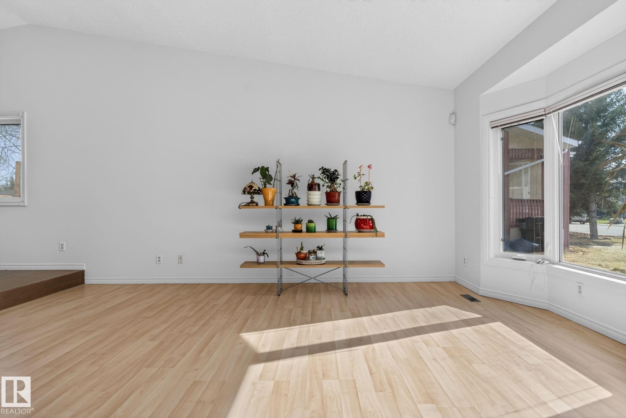 Spacious room featuring vaulted ceilings, light wood-finish flooring, and a multi-panel bay window - 8403 190 Street, Edmonton, AB - Indoor Photo Showing Other Room