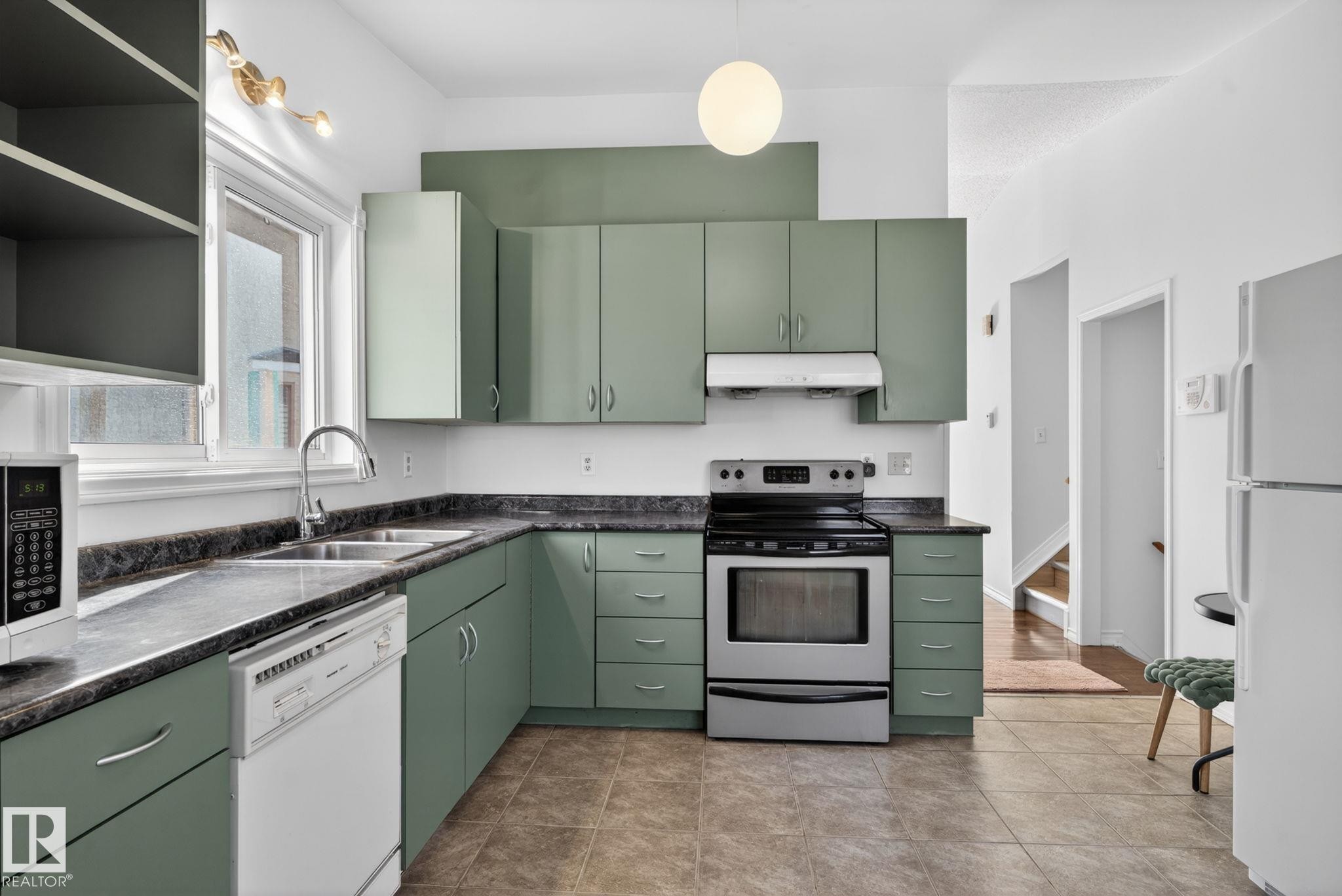 Kitchen featuring green cabinetry, dark countertops, a stainless steel range, and tile flooring - 8403 190 Street, Edmonton, AB - Indoor Photo Showing Kitchen With Double Sink